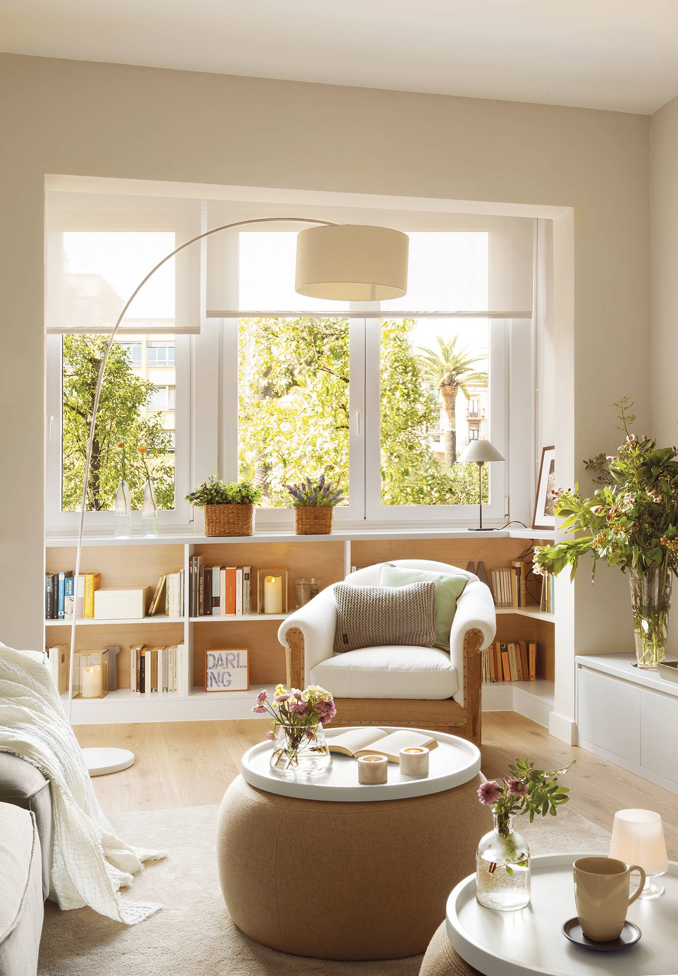 Salón de estilo nórdico decorado en color blanco con una librería baja situada bajo la ventana 00406035