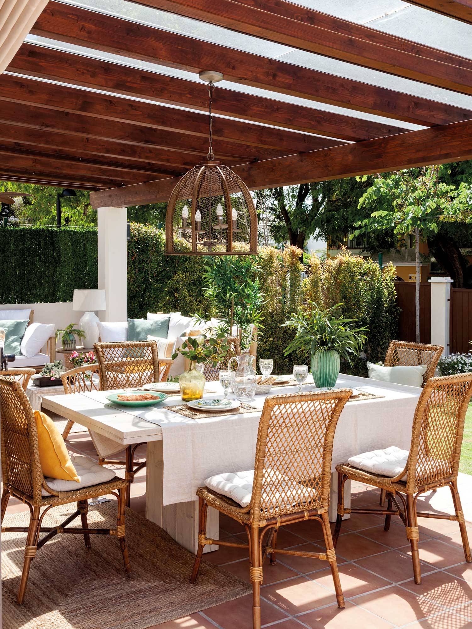 Comedor exterior con mesa blanca y elementos decorativos en tonos blancos. 