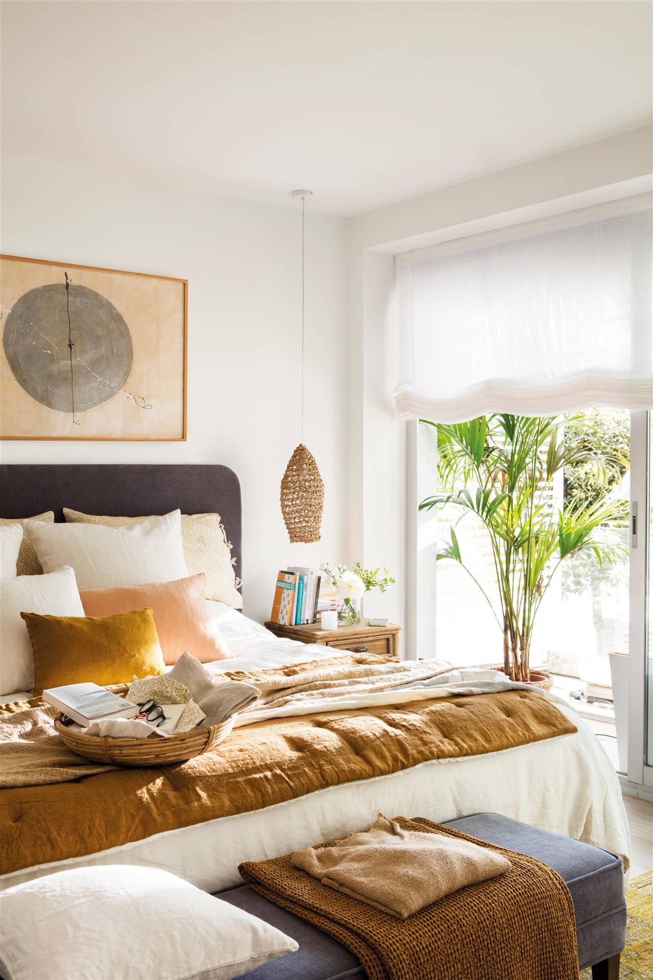 Dormitorio con cabecero tapizado y lámparas colgantes a ambos lados de la cama. 