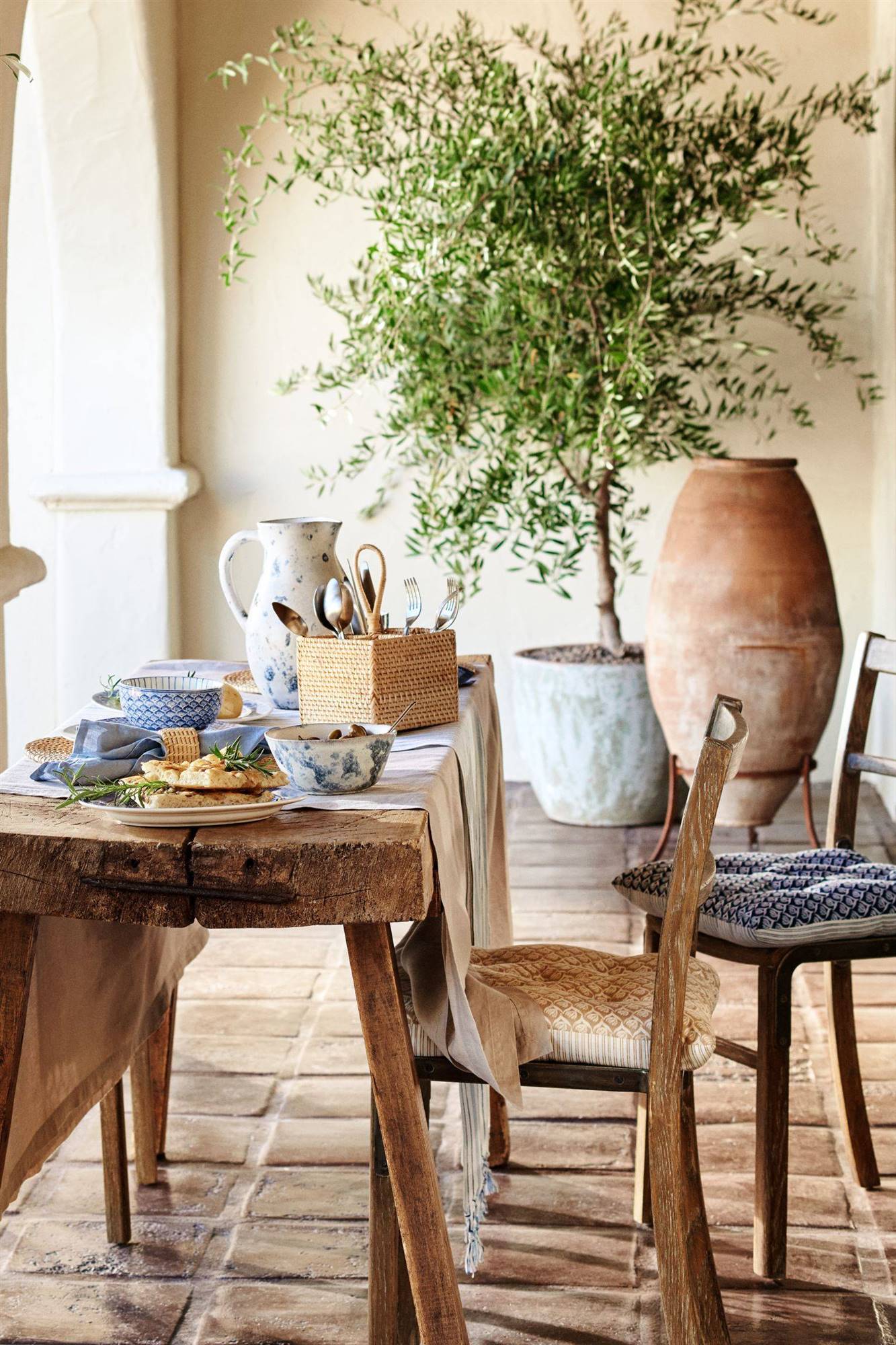 Mesa de verano con cesta de ratán y vajilla azul de H&M Home