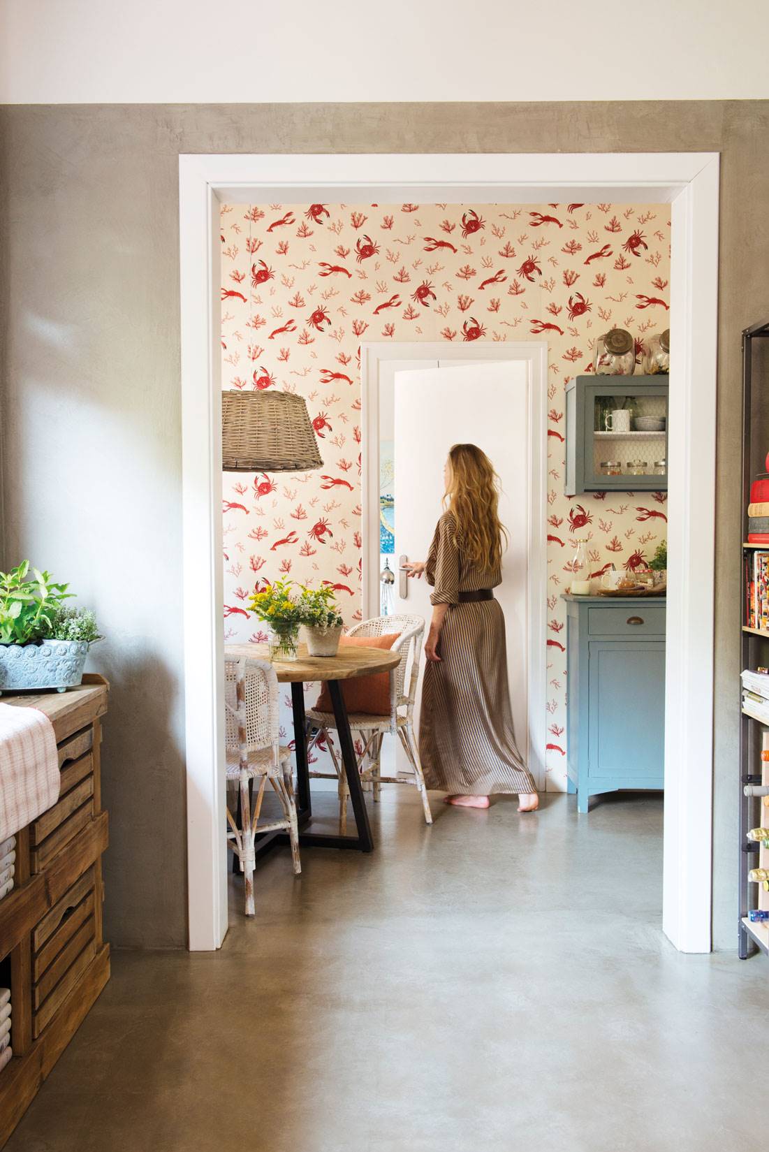 Mujer entrando en cocina con papel pintado de flores rojas y suelo de microcemento 485201