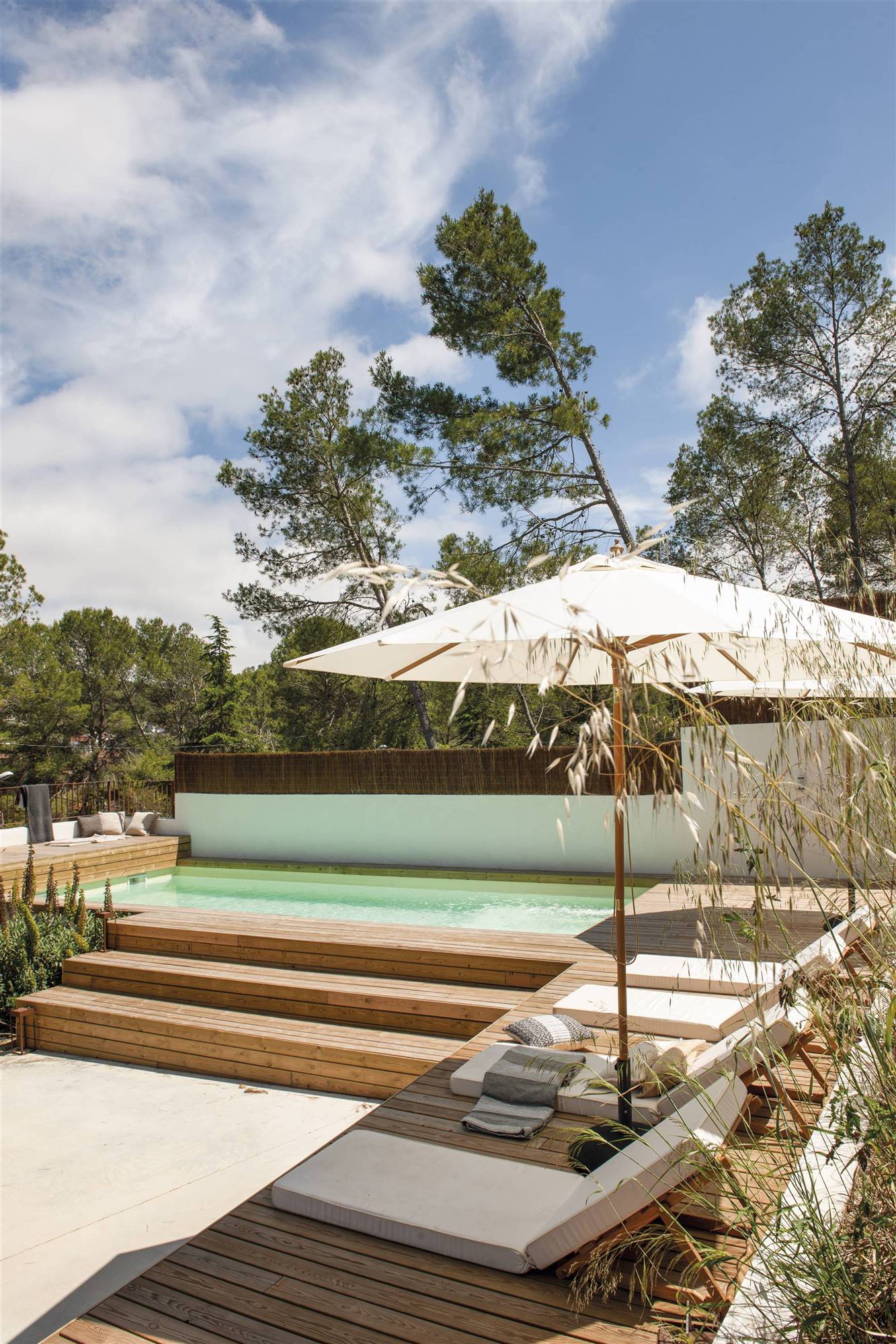 Una piscina elevada con acabado en madera y tumbonas alrededor