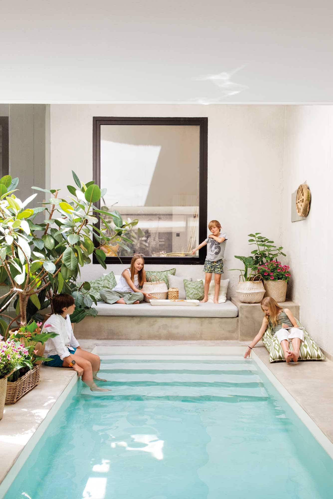 Una piscina interior con sofá hecho a medida y rodeada de plantas de interior