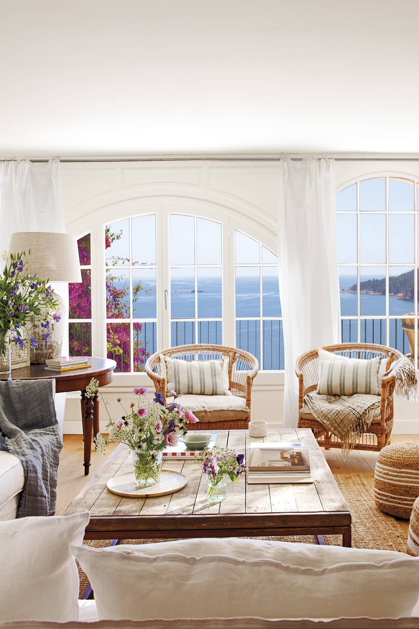 Un salón blanco con grandes ventanales con vistas al mar 