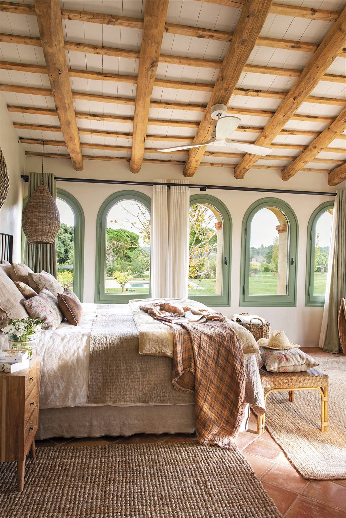 Dormitorio de masía con vigas y ventanales con vistas al jardín