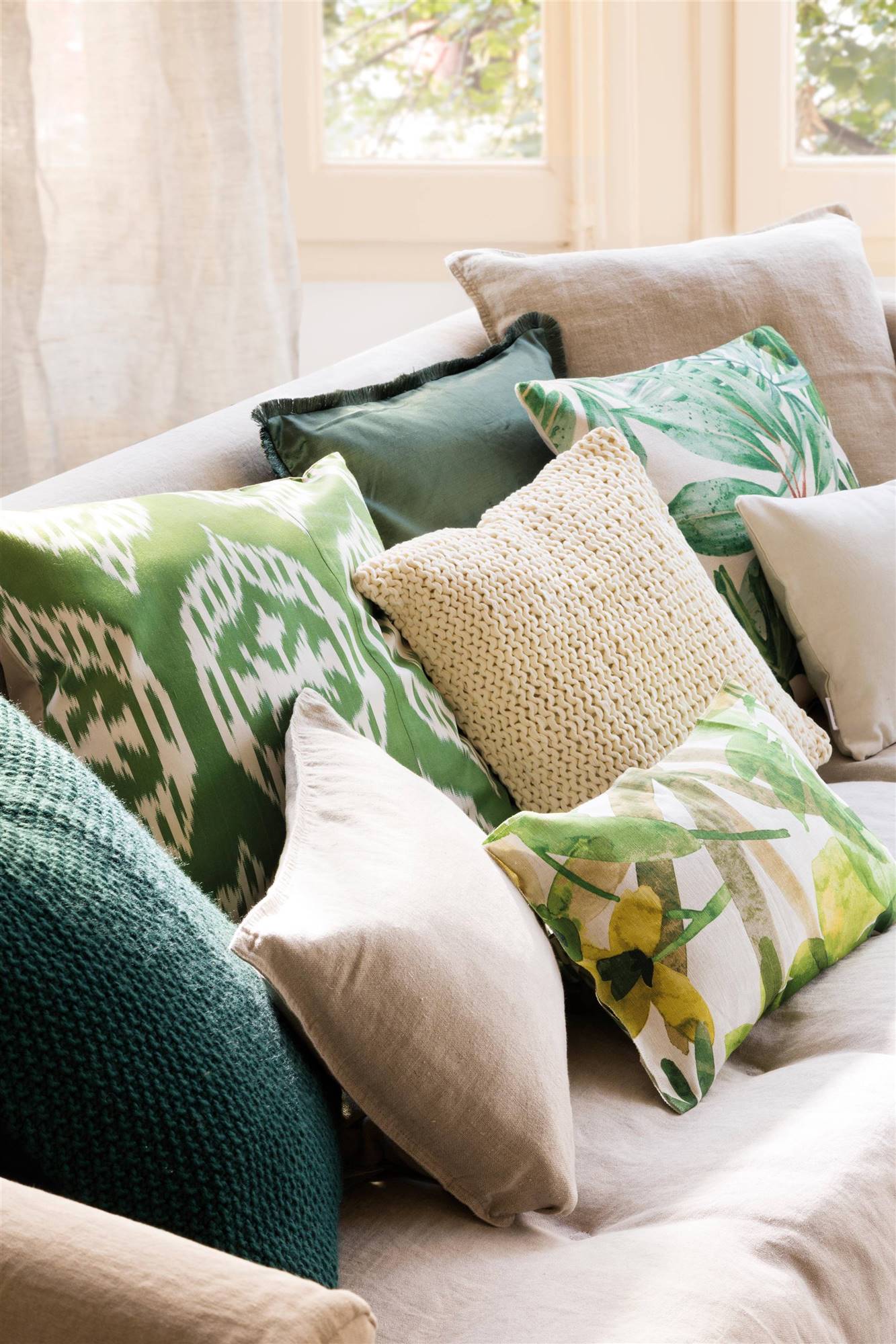Cojines de color verde sobre un sofá blanco. 