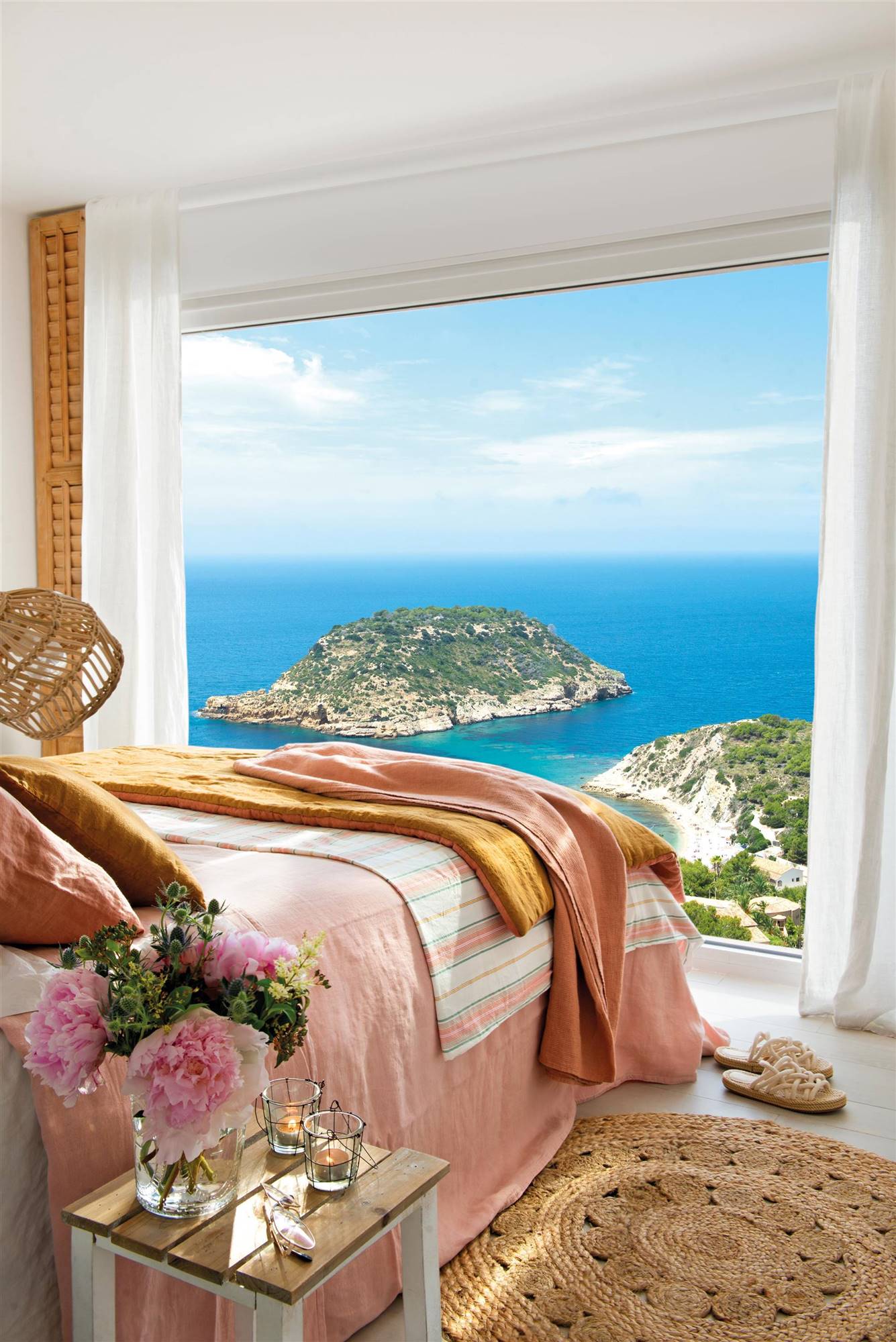 Dormitorio de verano con vistas al mar y ropa de cama rosa. 
