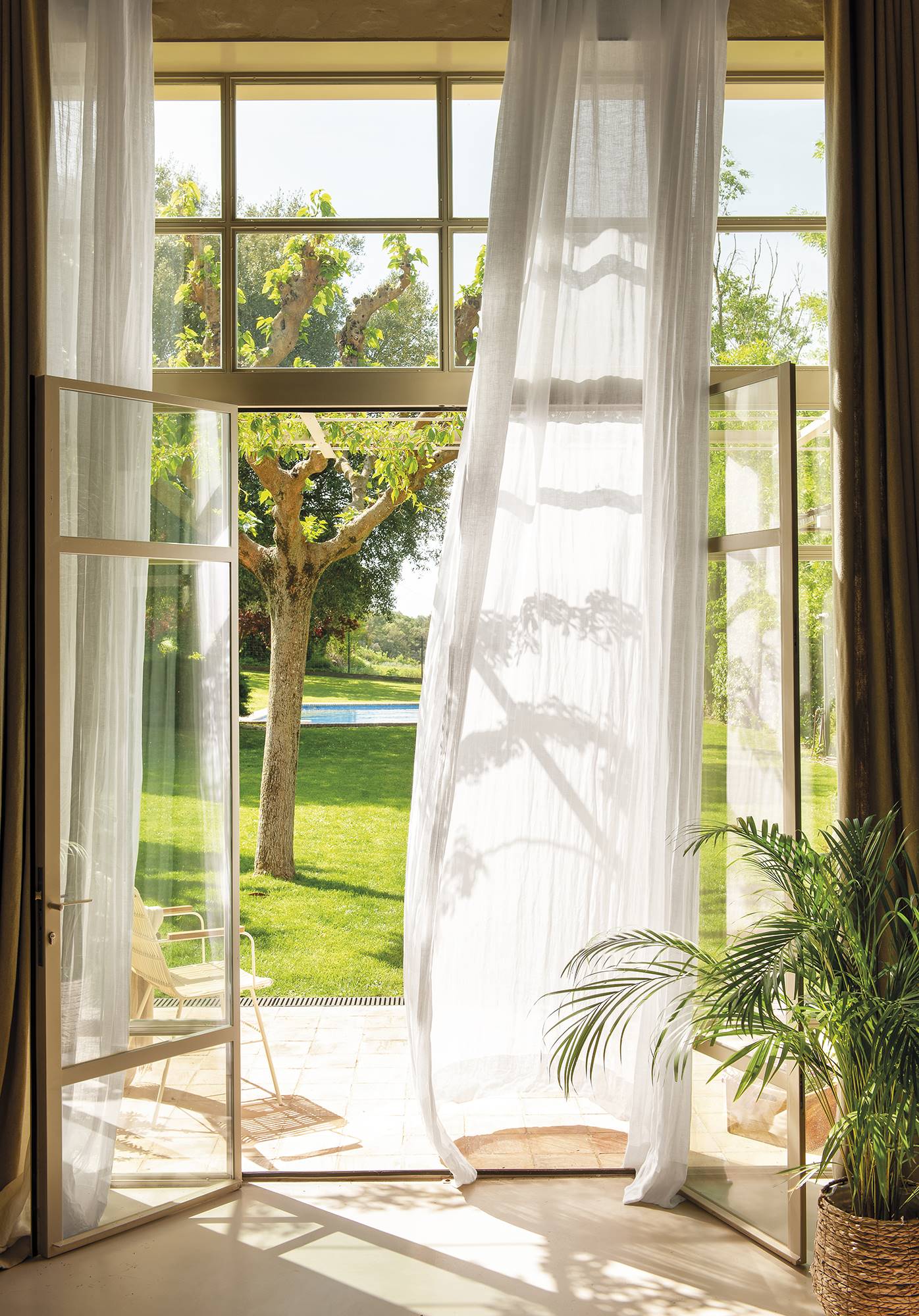 Ventanal con cortina vaporosa y vistas al jardín. 