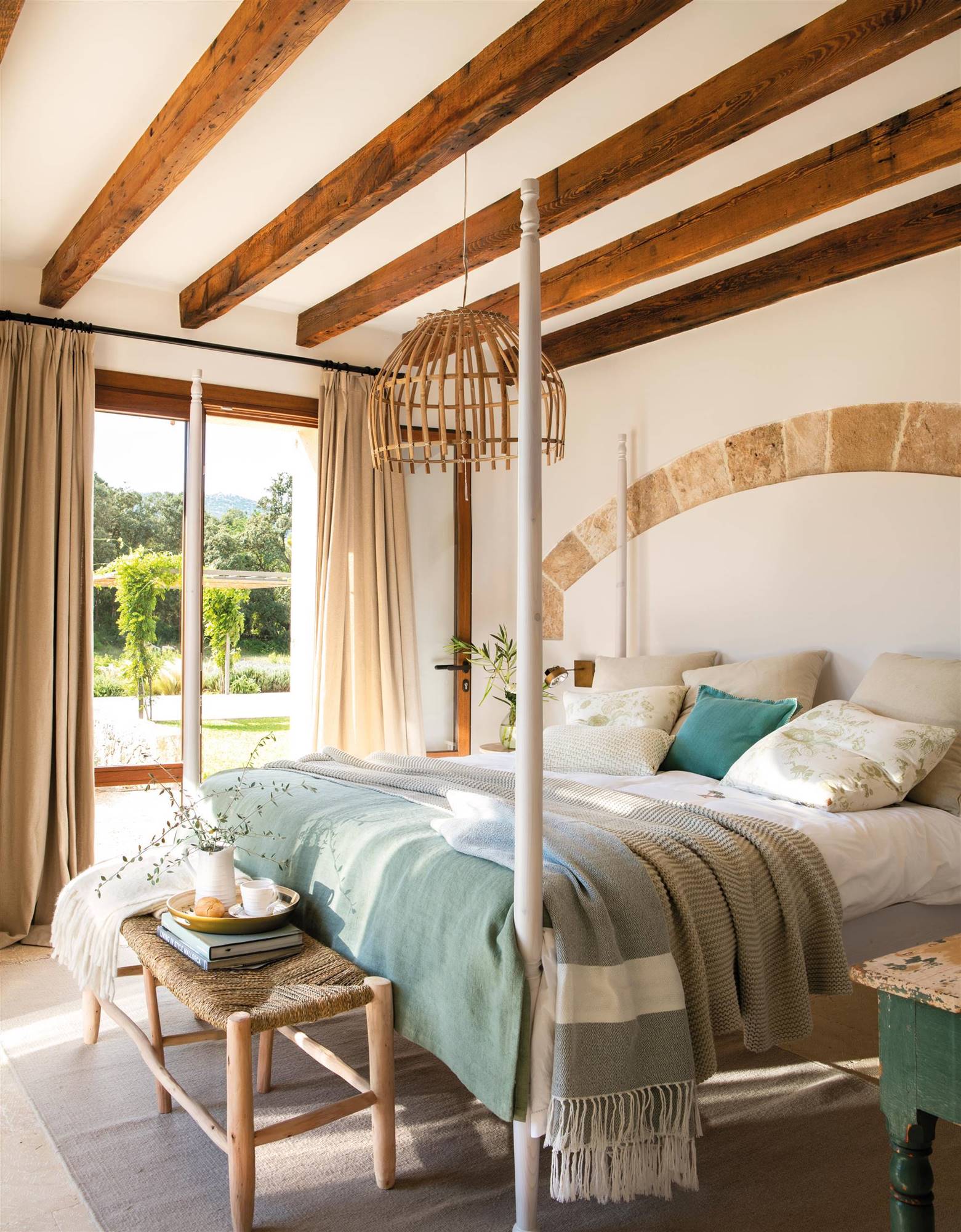 Dormitorio con cama con dosel, vigas de madera y revestimiento en arco en zona de cabecero