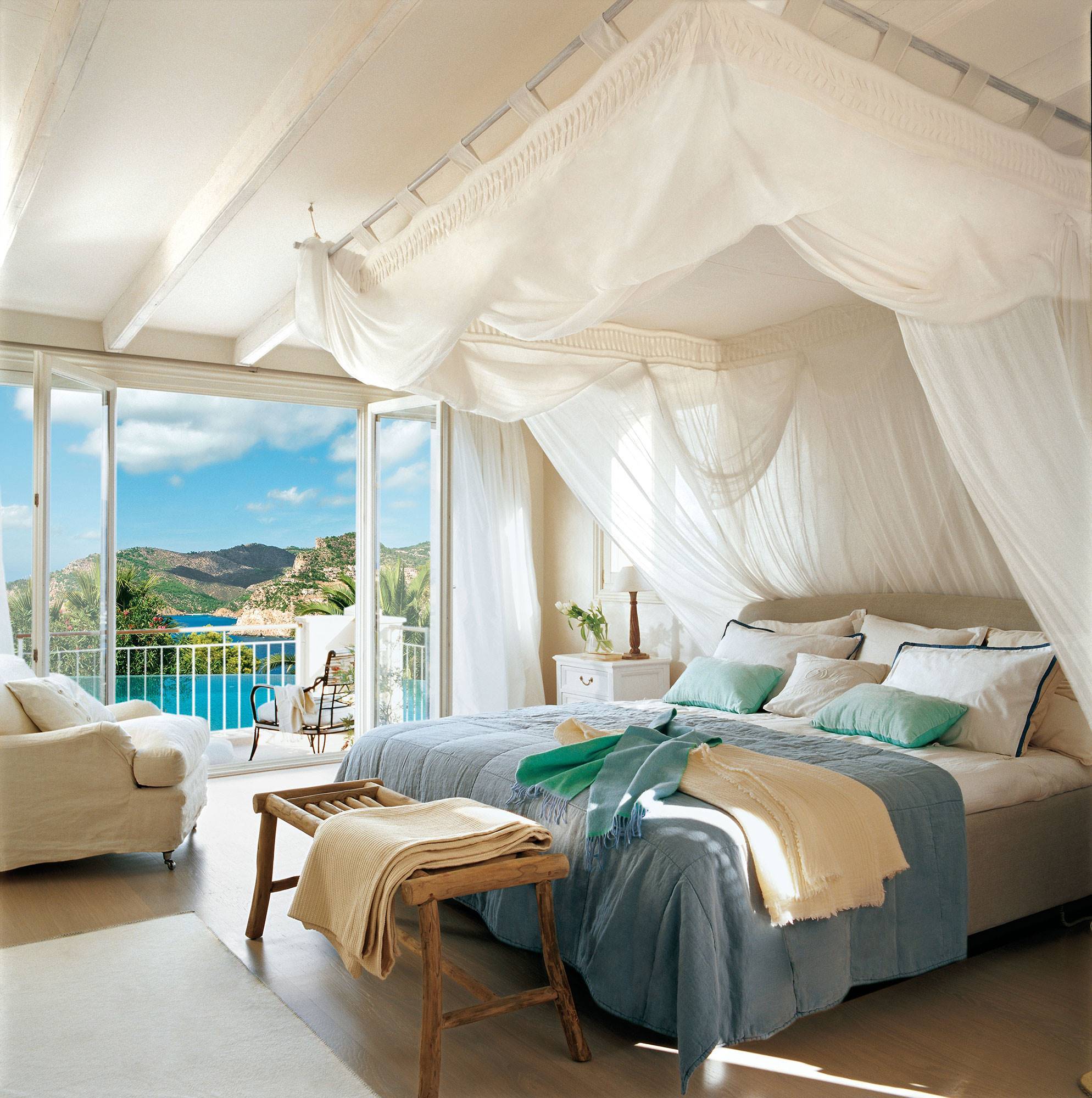 Dormitorio con cama con dosel blanco y vistas al mar. 
