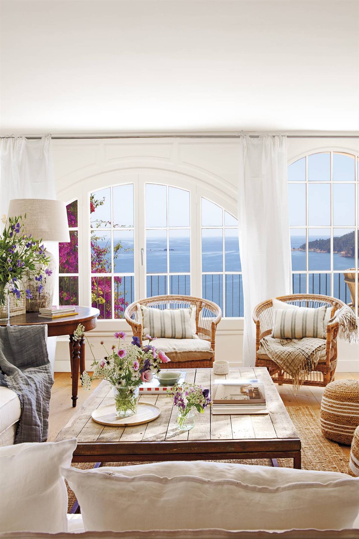 Salón de apartamento de verano con paredes blancas y ventanales con vistas al mar