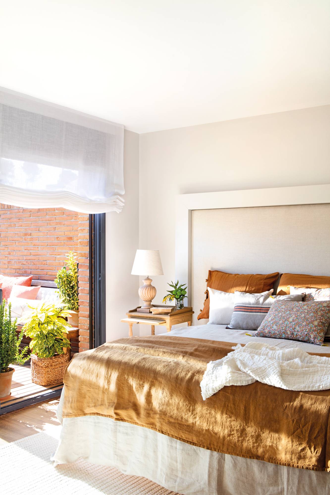Dormitorio con ropa de cama en tonos ocres y cabecero de cama hecho con listones de madera 00503850