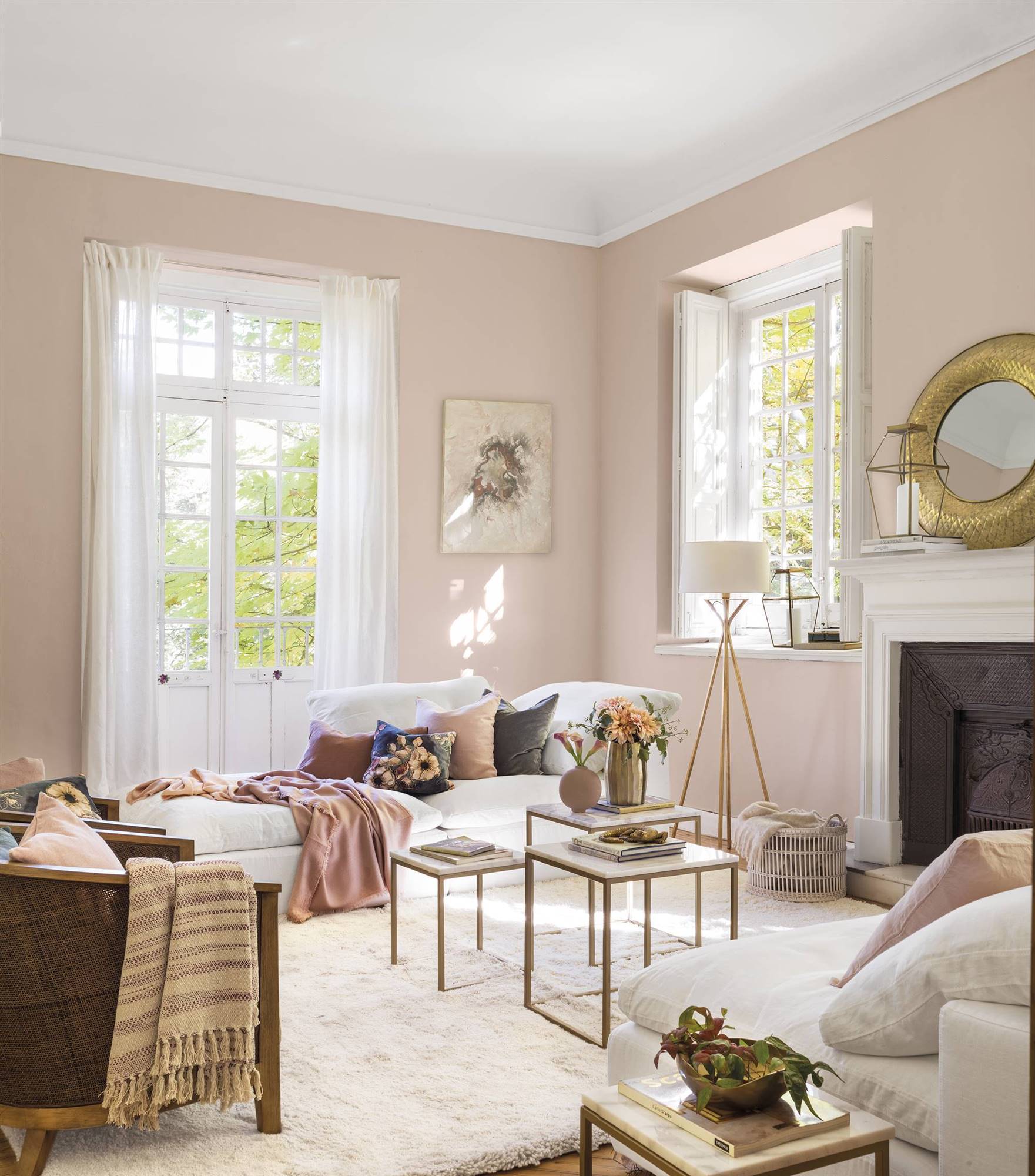 Salón con chimenea y paredes rosas, diván tapizado en blanco, mesas auxiliares de mármol y estructura dorada 00497467