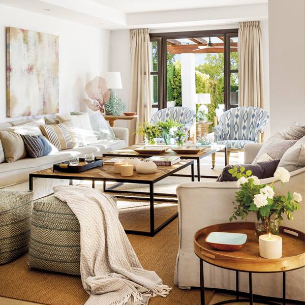 Salón con sofás de lino beige, pufs étnicos, alfombra de fibras y mesas de centro 00526262