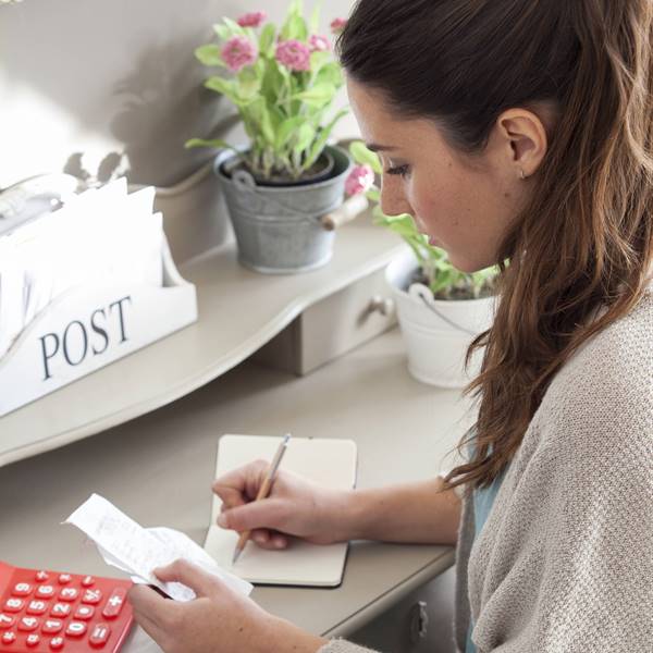 mujer escribiendo en un cuaderno y haciendo las cuentas del mes