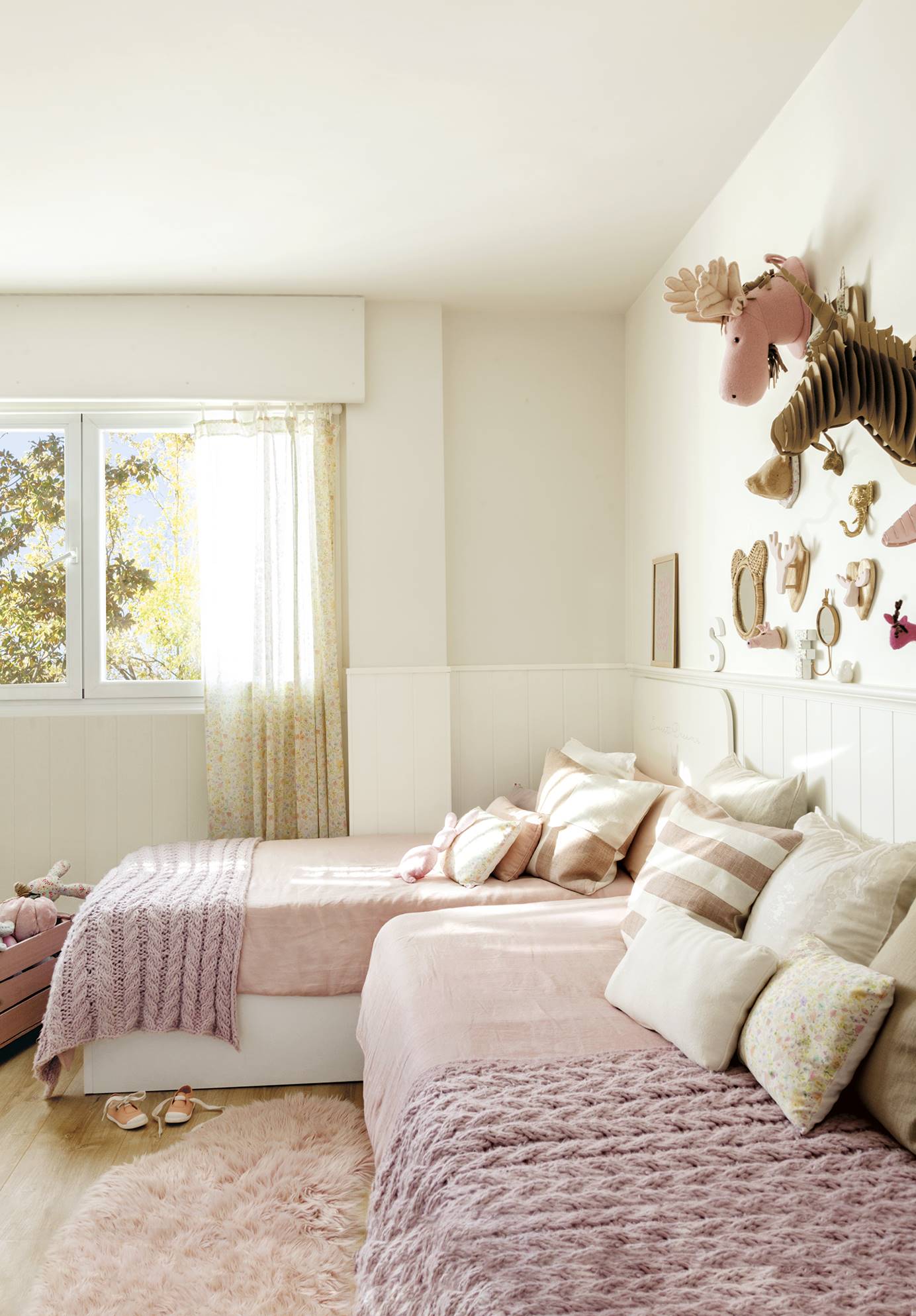 Habitación infantil con ropa de cama en color fresa claro y arrimadero blanco en la pared. 