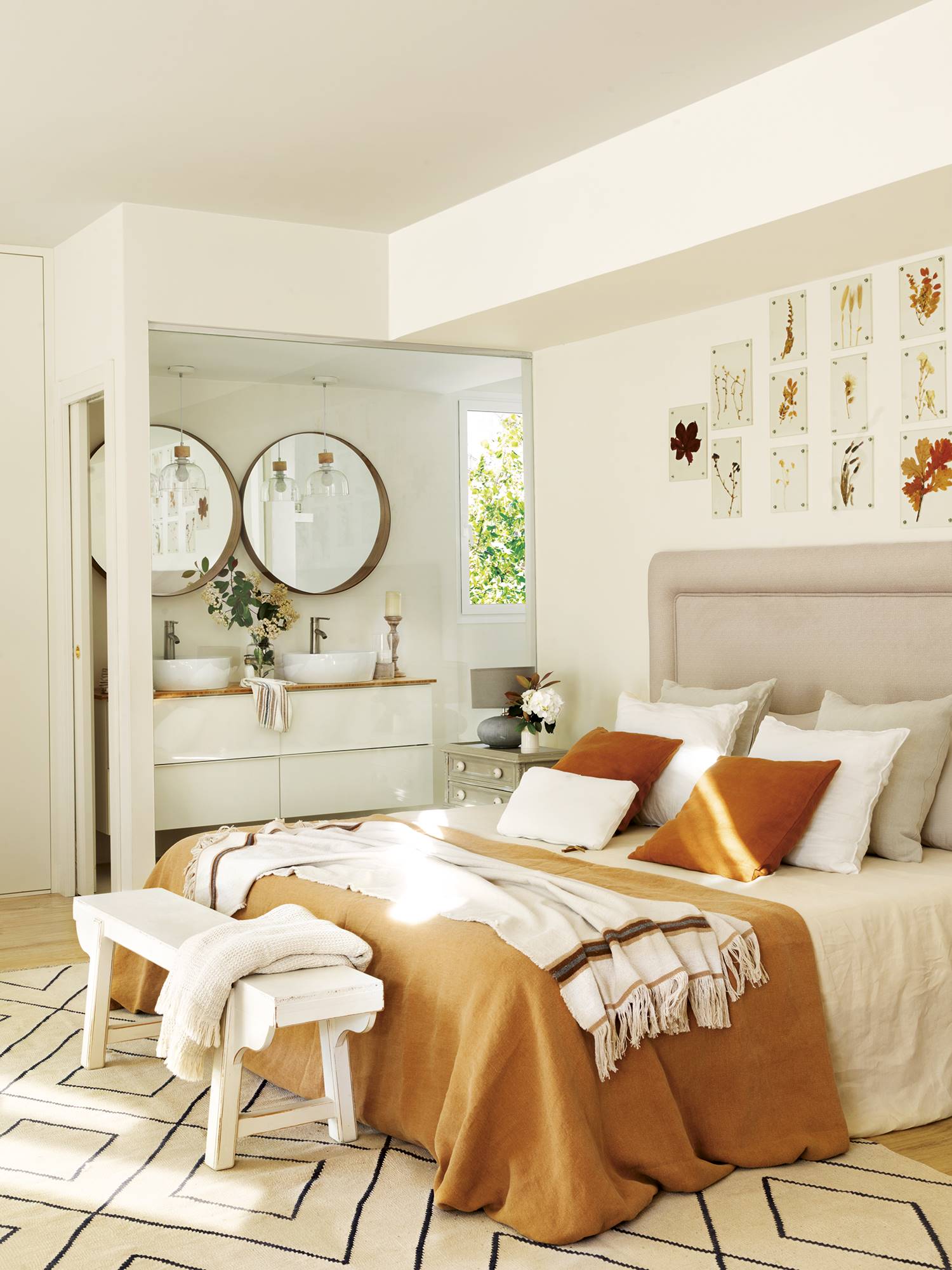 Dormitorio con alfombra, cama, banco, cabecero tapizado y baño abierto  la habitación. 