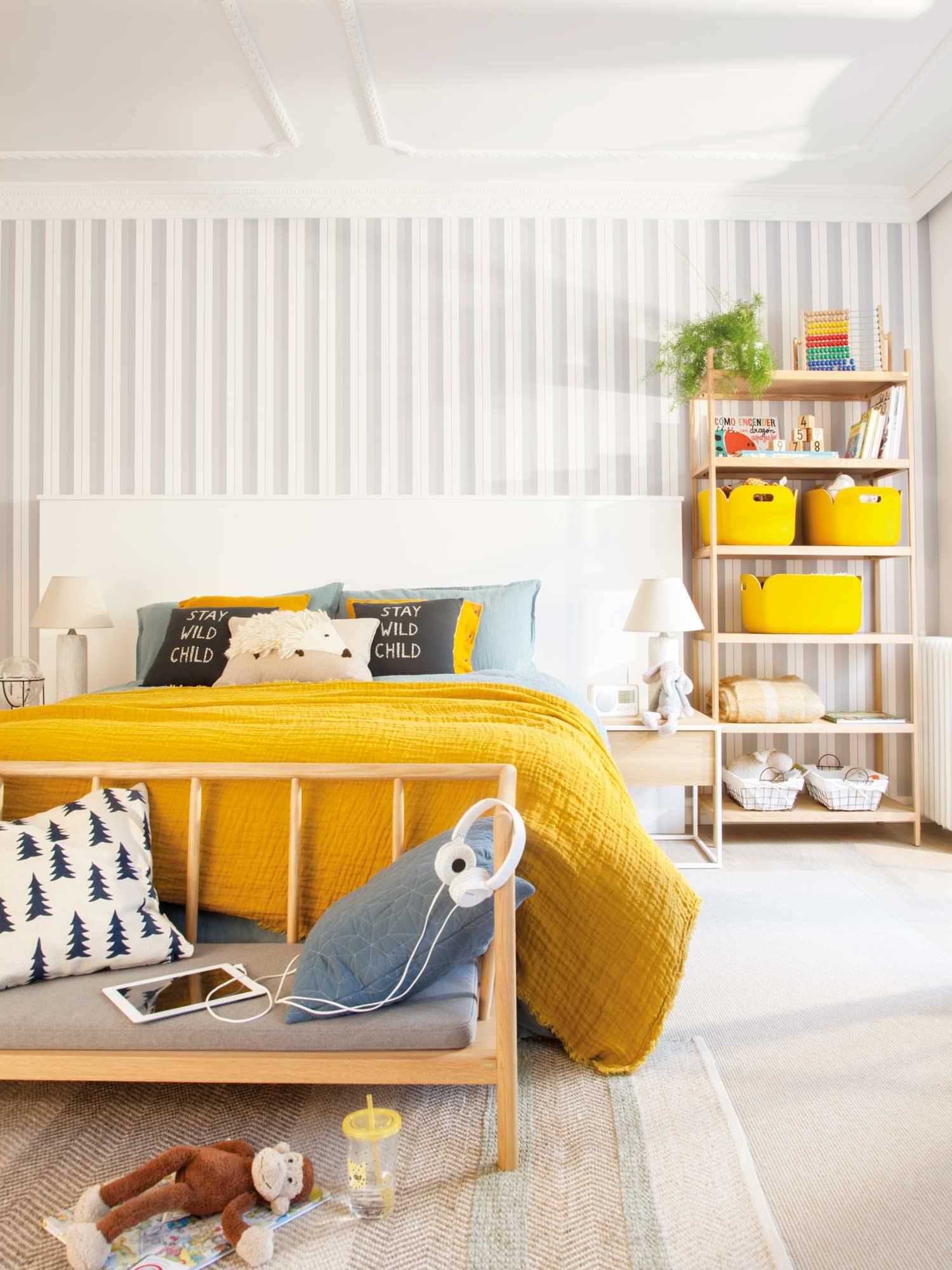 Dormitorio juvenil con papel pintado de rayas y ropa de cama de color mostaza. 