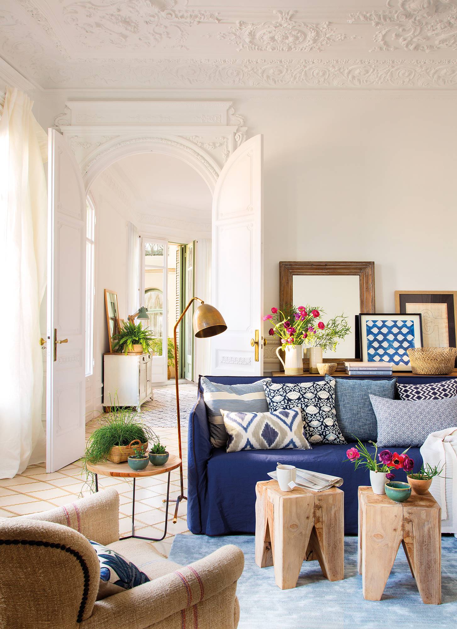 Salón señorial con sofá de lino azul, mesas auxiliares de madera estilo taburetes, alfombra de pelo azul y butaca clásica 00454748