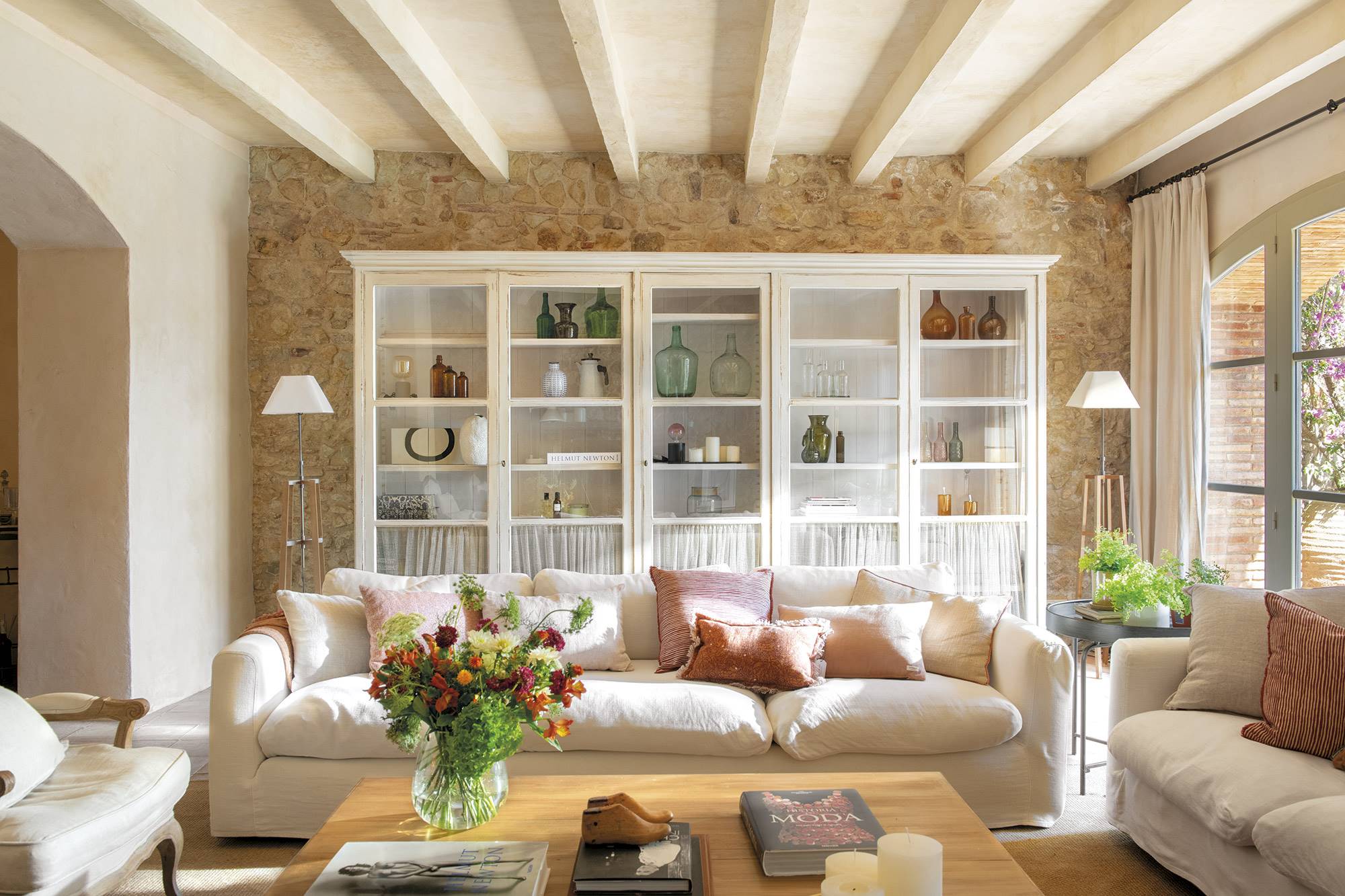 Salón con librería, vigas, sofá y pared de piedra.