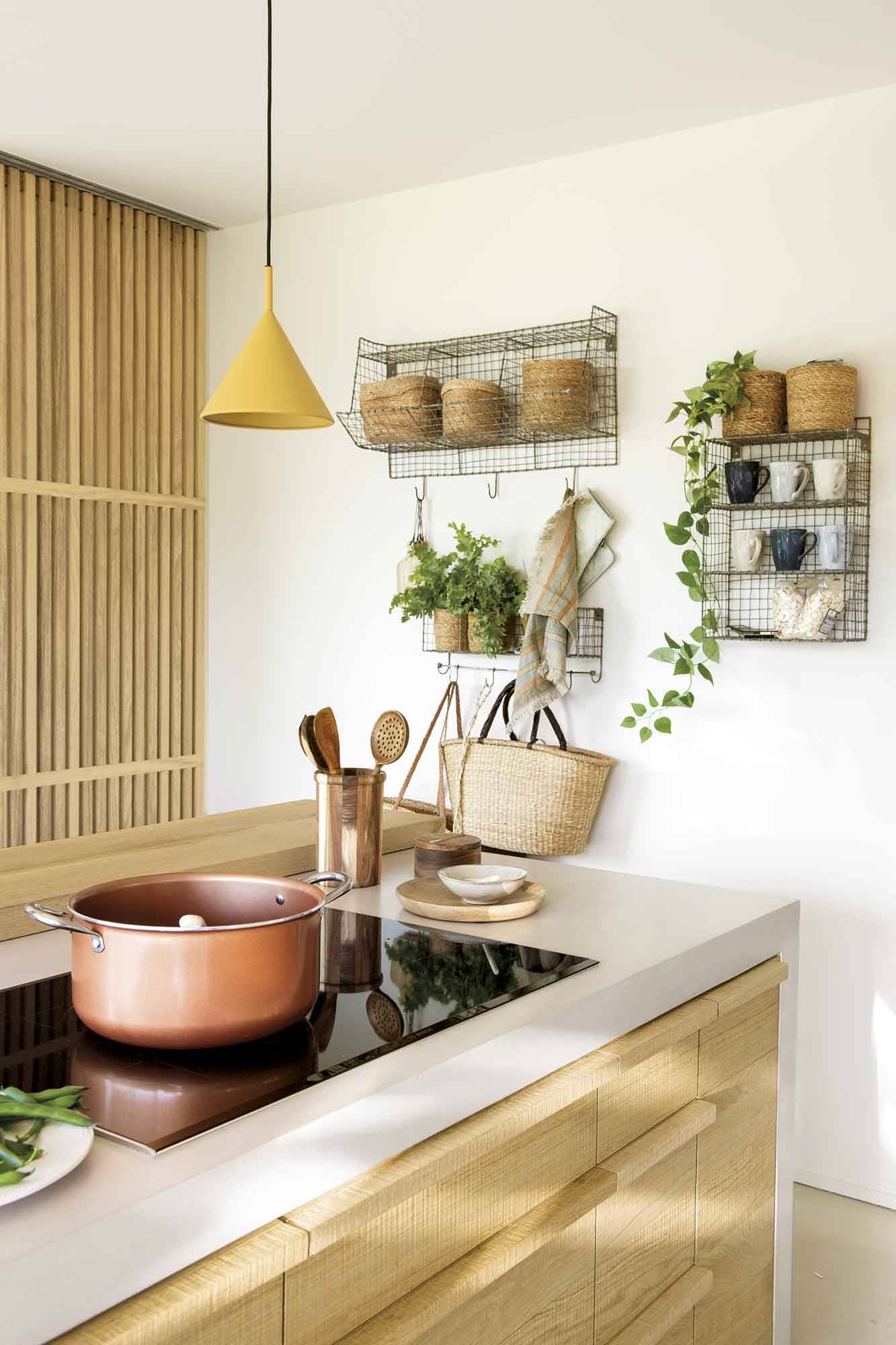 Detalle de la cocina con estantes metálicos, cestos y plantas. 