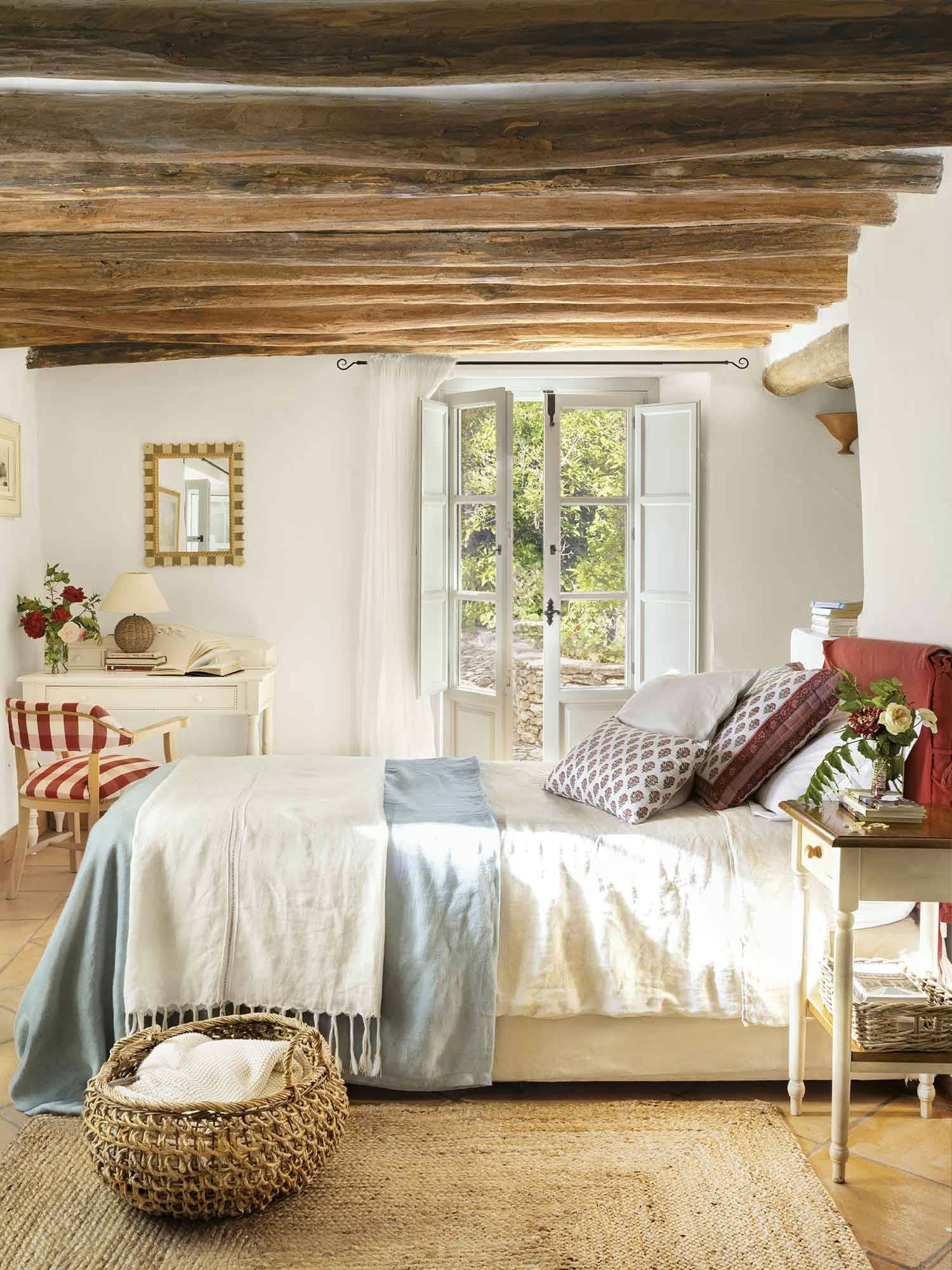 Dormitorio con vigas de madera y cabecero granate tapizado.