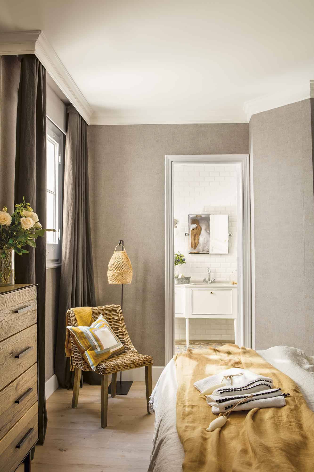 Dormitorio con papel pintado gris y acceso al baño.