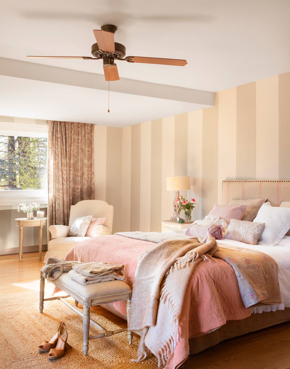 Dormitorio clásico romántico con papel pintado a rayas, cama con cabecero tapizado y banco afrancesado a los pies de la cama 00421022