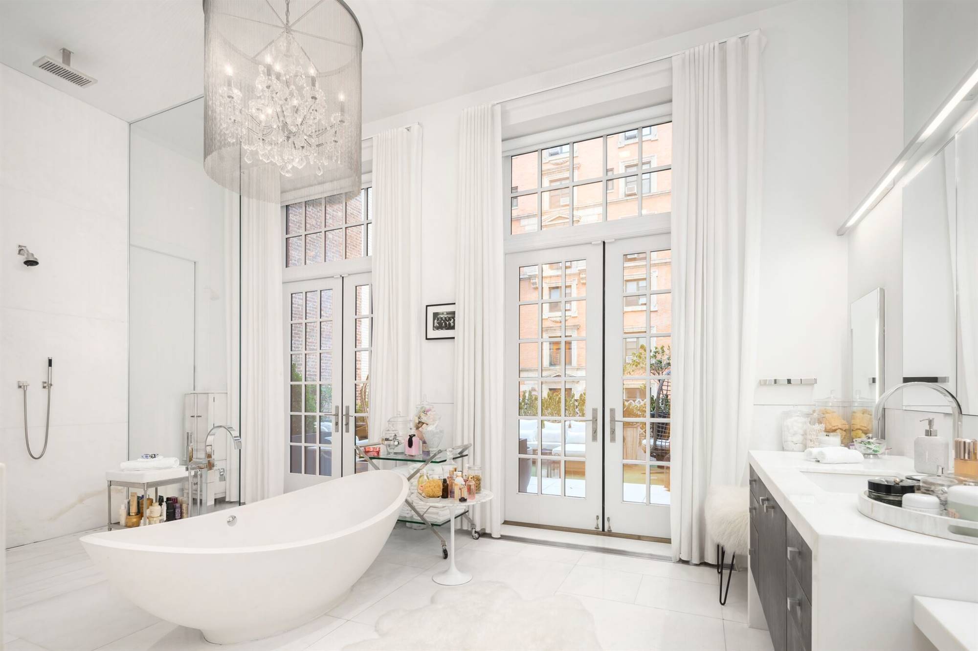 Baño con ducha, bañera exenta y suelo de mármol en el ático de Jennifer López en Nueva York