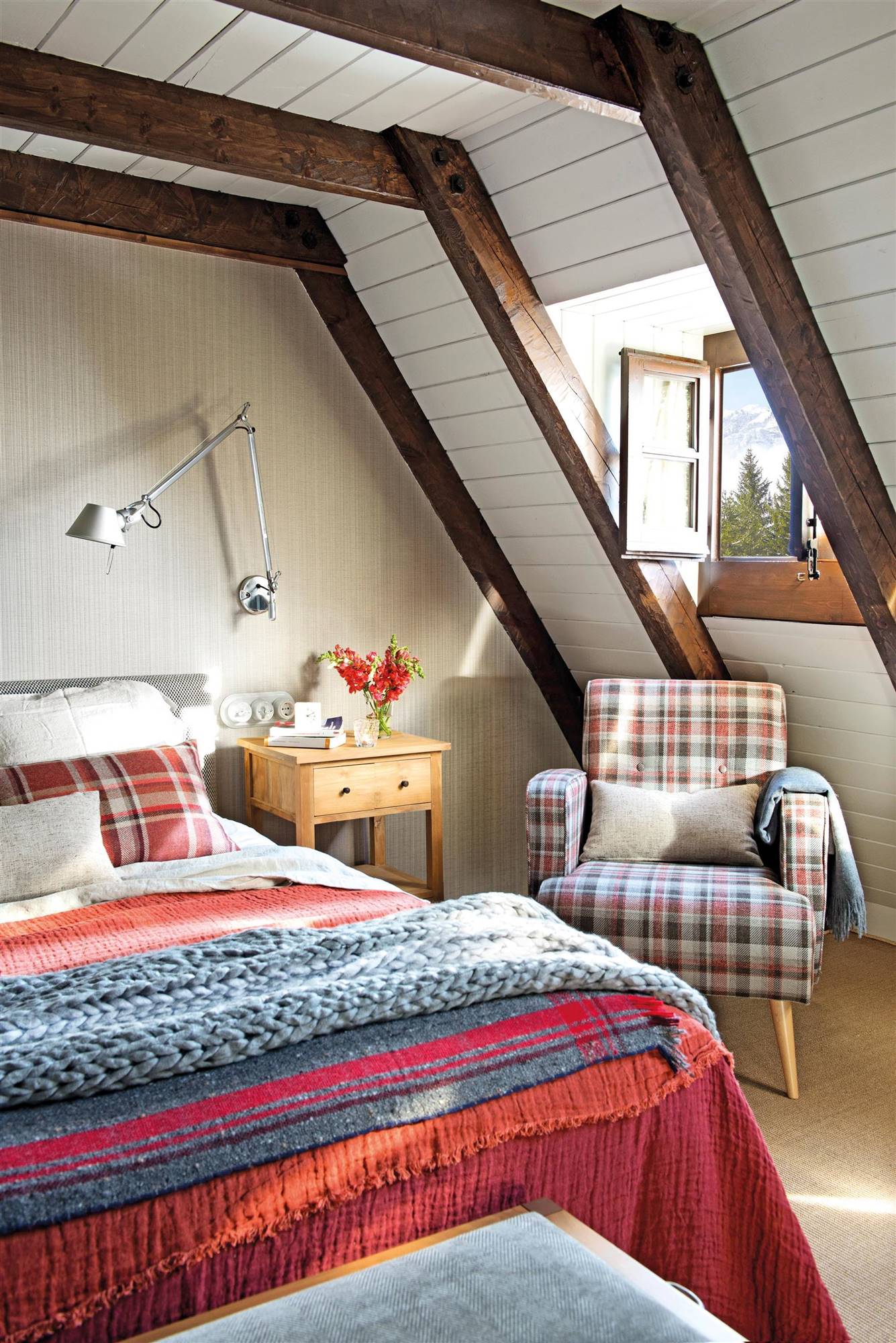 00520083 Dormitorio con butaca con tapicería de cuadros y ropa de cama en tonos rojos y azules