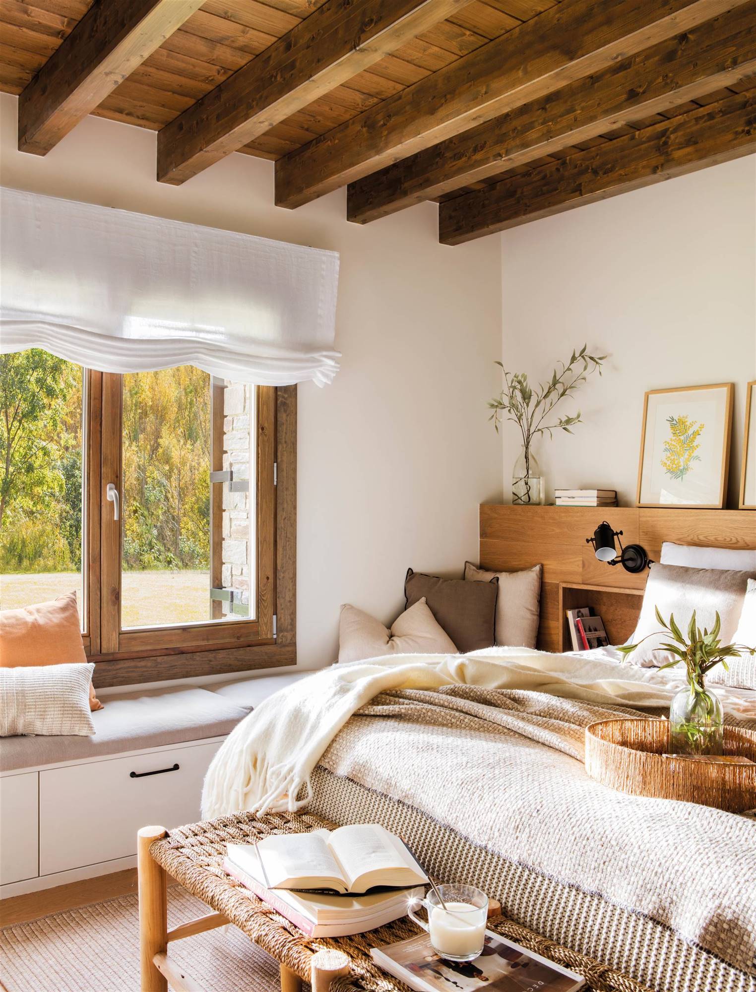 Dormitorio con cabecero de madera, vigas en el techo y banco a los pies.