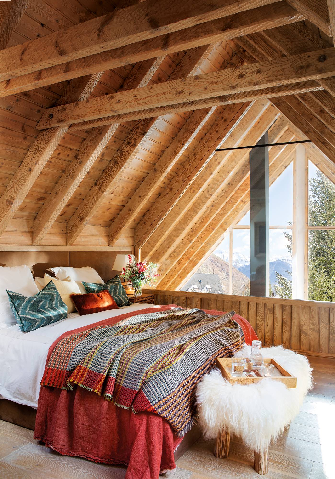 Dormitorio de invierno revestido en madera con vigas y banco de pelo.