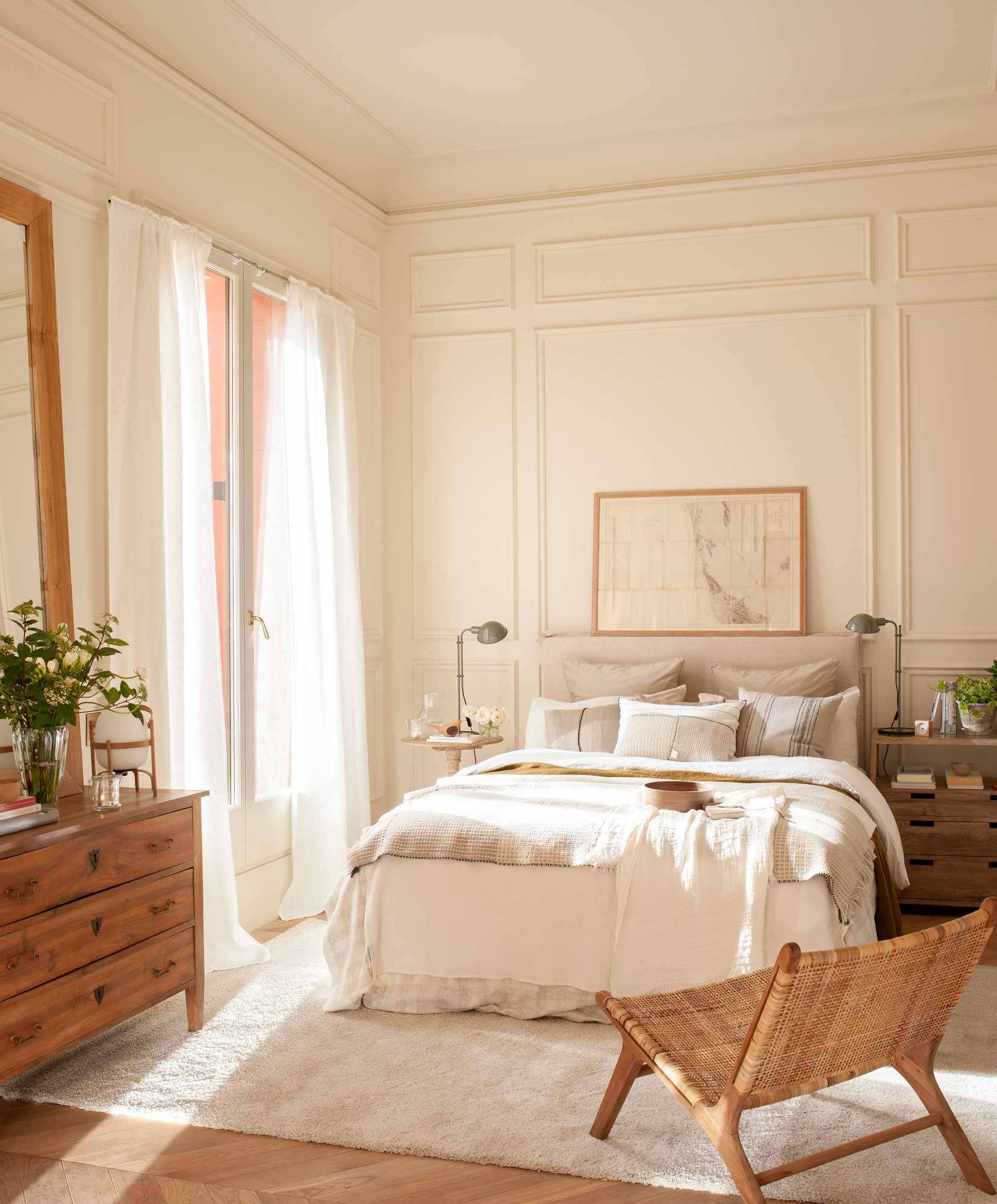 Dormitorio clásico con molduras en la pared y muebkes de madera. 