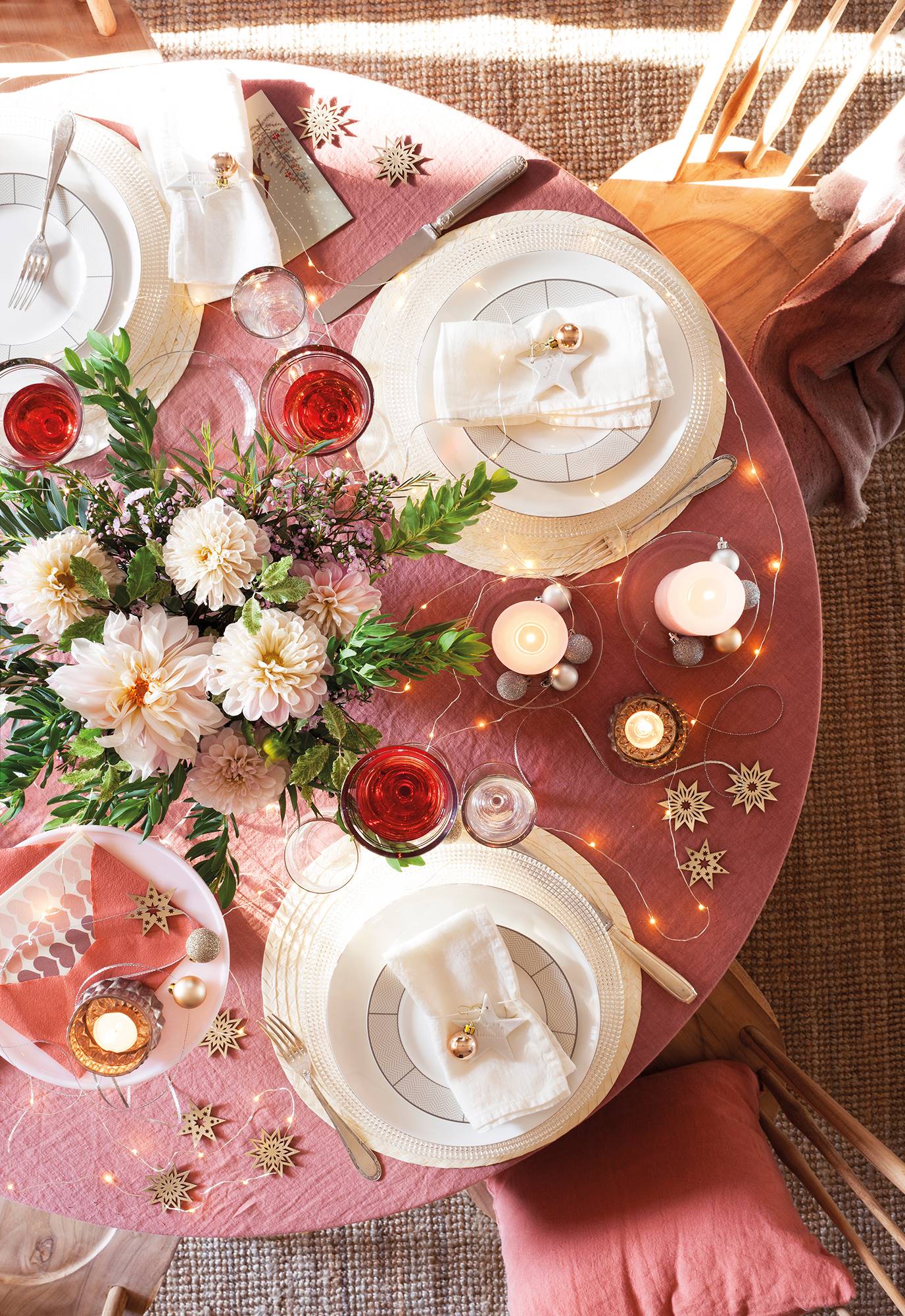 Comedor con mesa de Navidad con mantel de color rosa y adornos. 