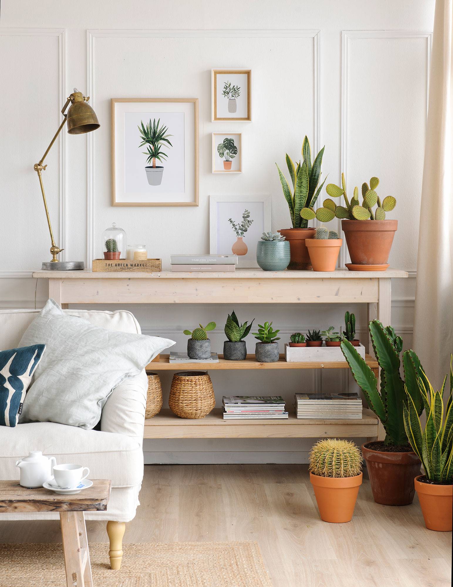 Rincón de salón con mueble en estantes, plantas y composición de cuadros con motivos vegetales