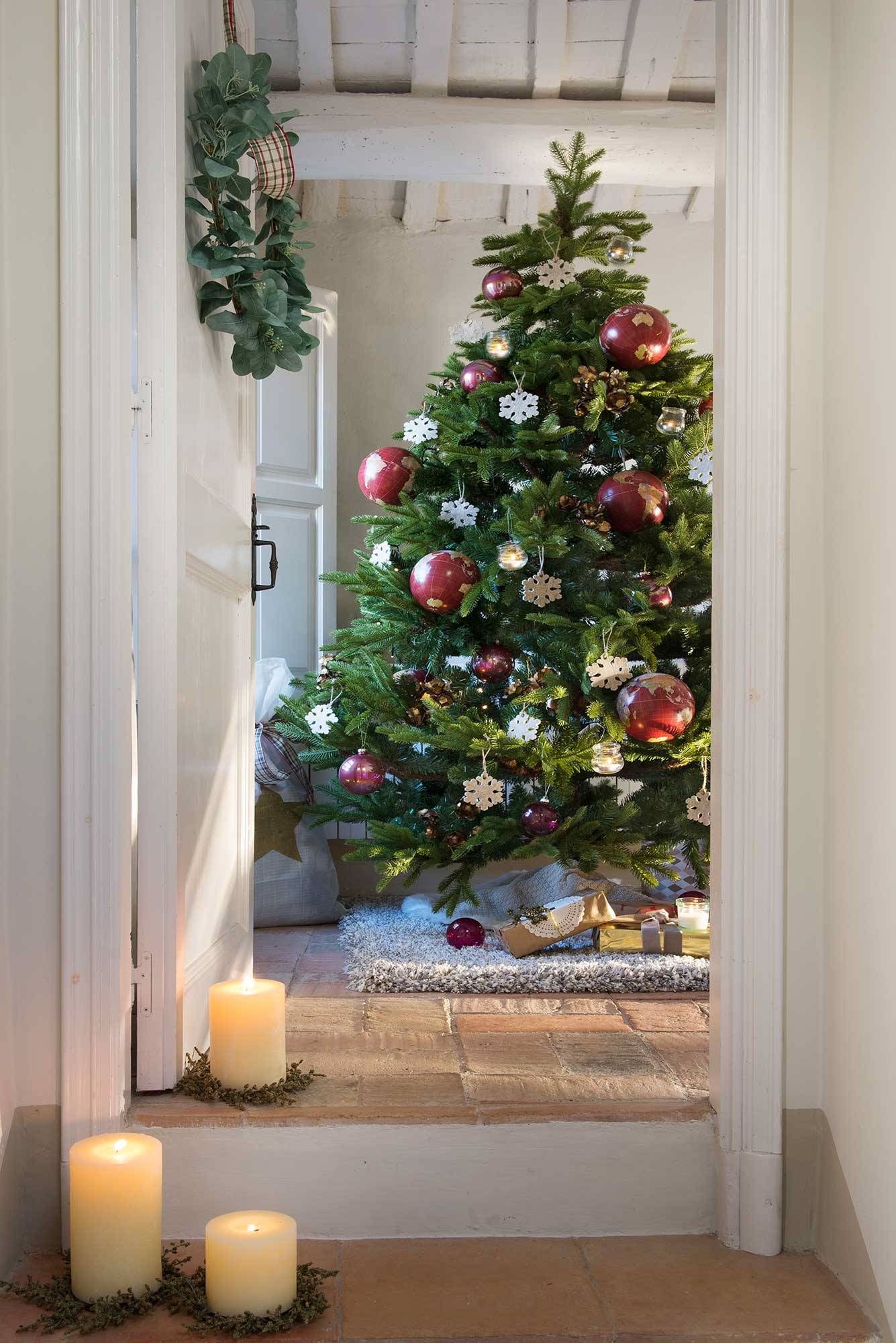 Recibidor con alfombra, velas, corona navideña en la puerta y árbol de Navidad.