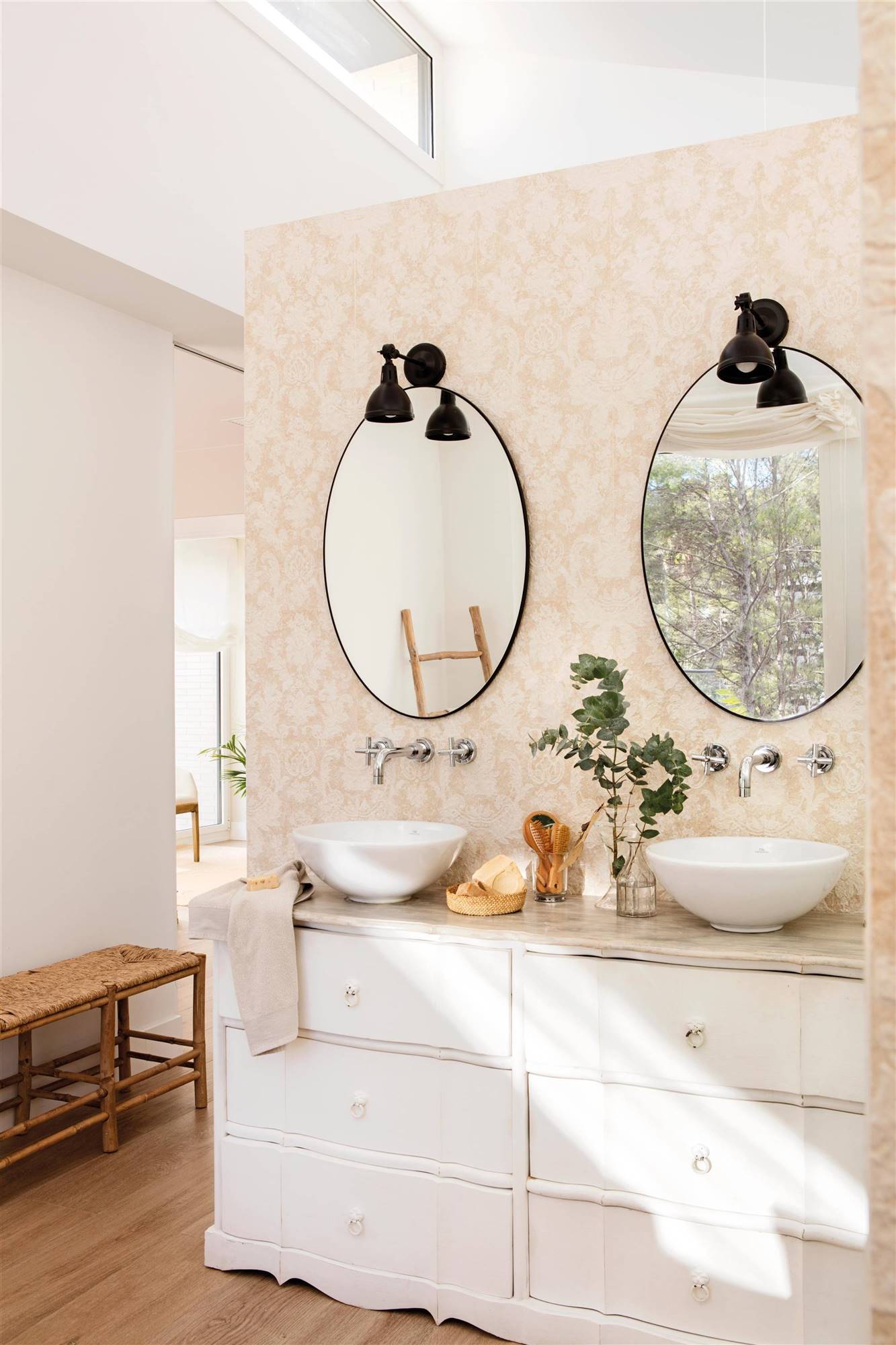Baño clásico con dos espejos negros redondos y cómoda restaurada. 