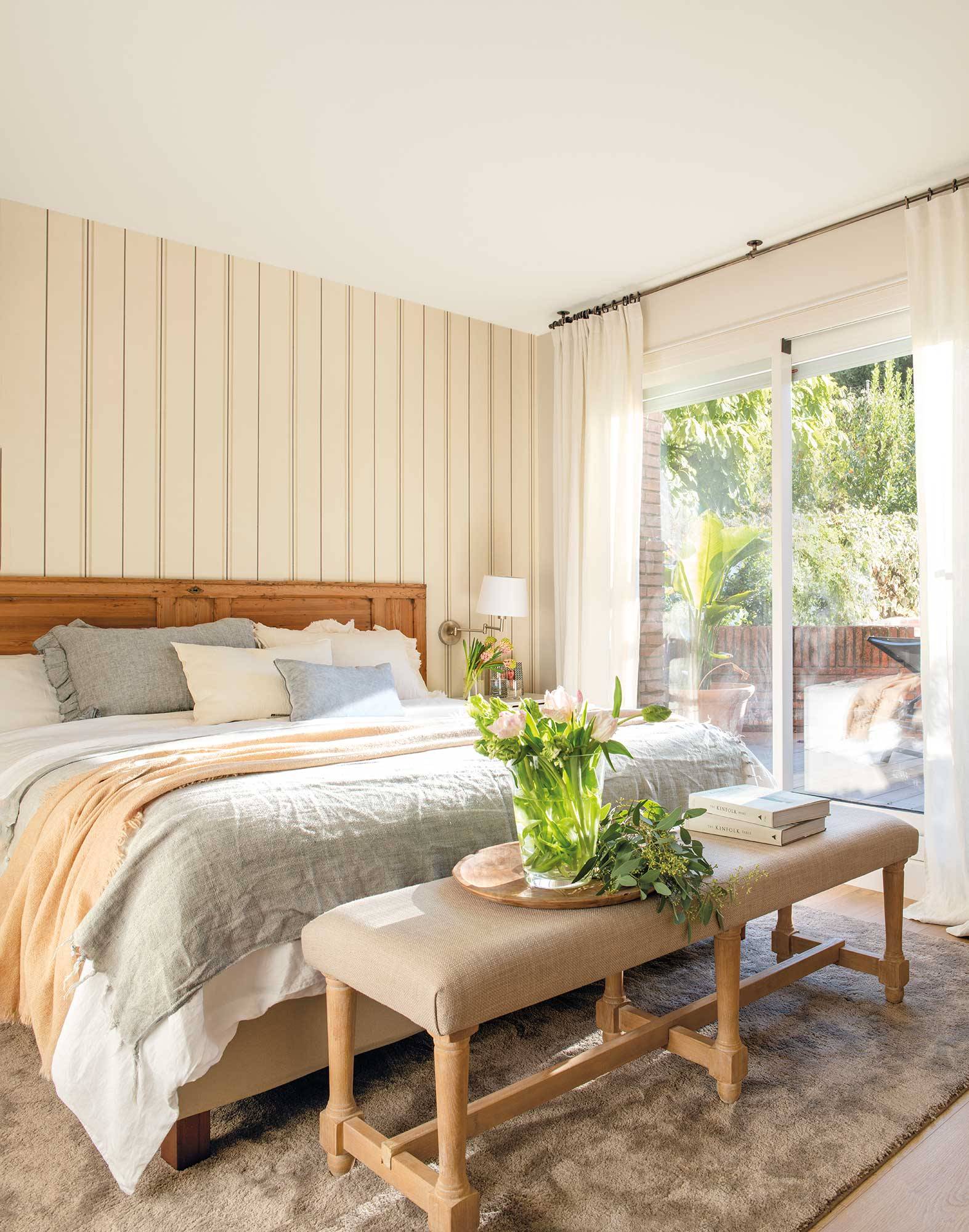 Dormitorio con papel a rayas en la pared y cabecero de madera