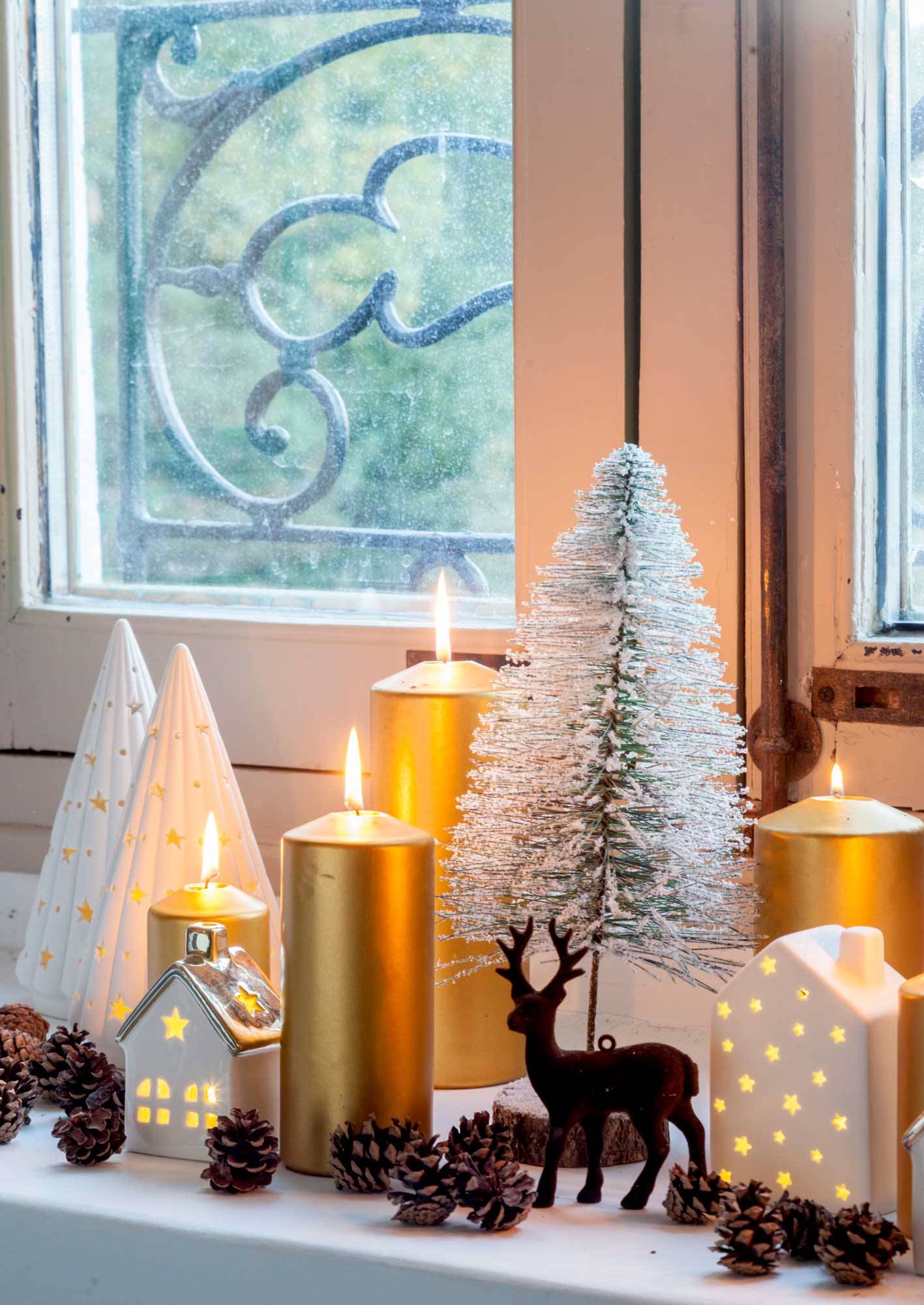 Repisa de una ventana decorada con velas y adornos de Navidad. 