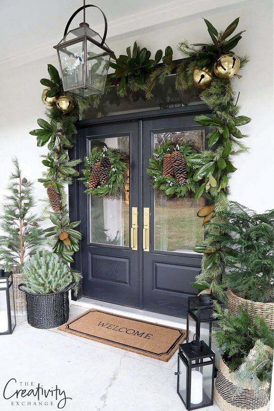 Puerta decorada con plantas y grandes bolas de Navidad.