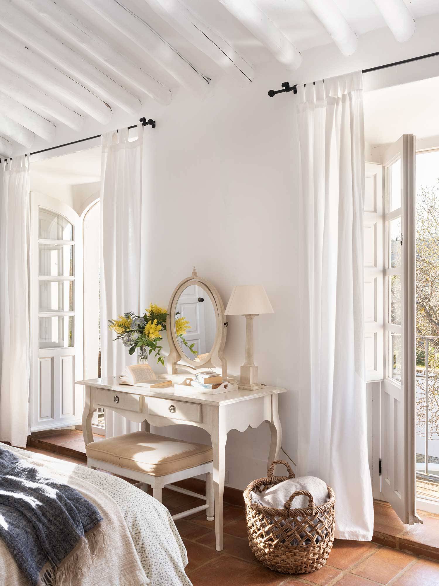 Dormitorio blanco con tocador a pie de cama.