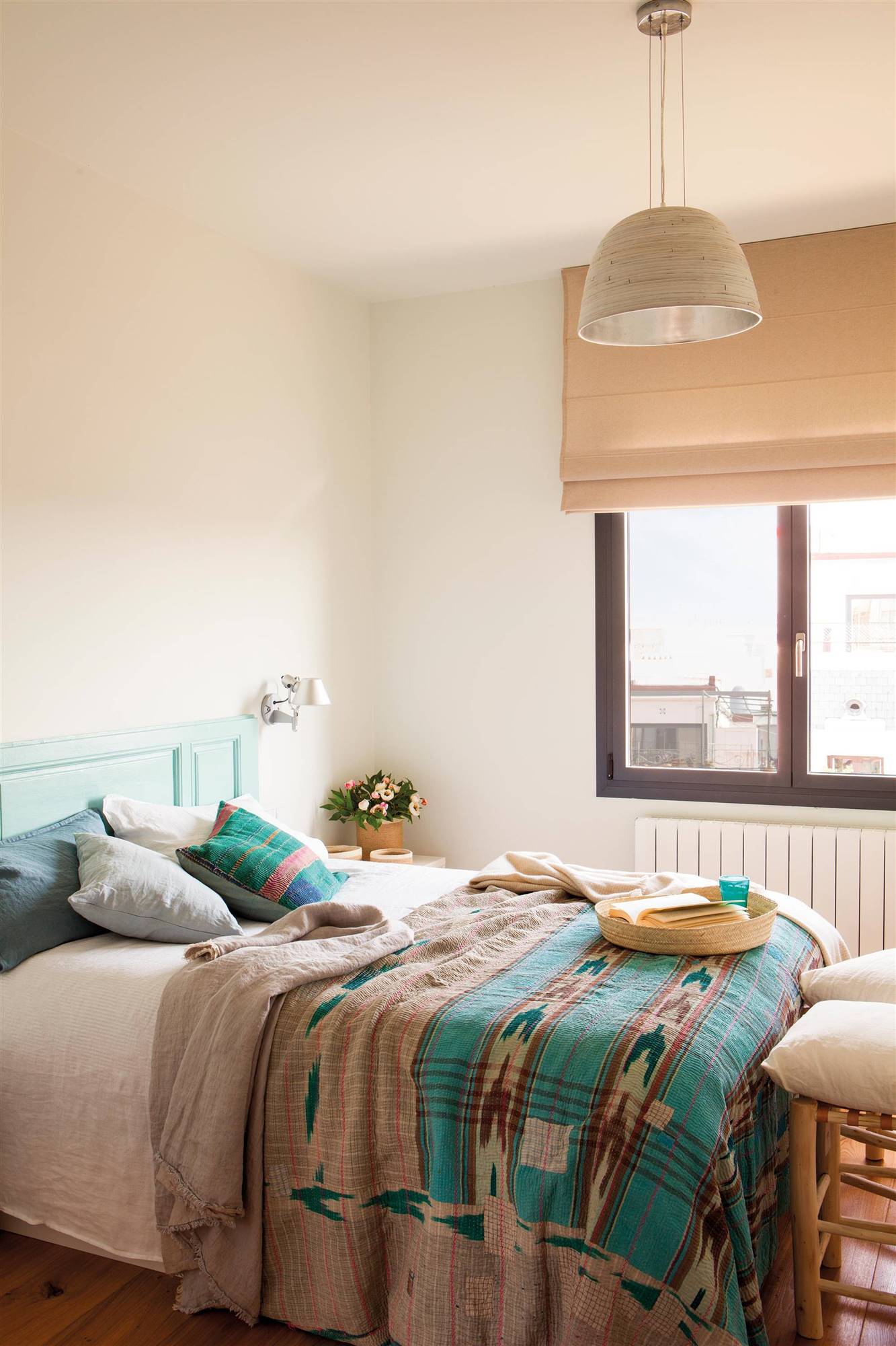 Dormitorio con ropa de cama étnica y cabecero azul realizado a partir de una puerta antigua. 