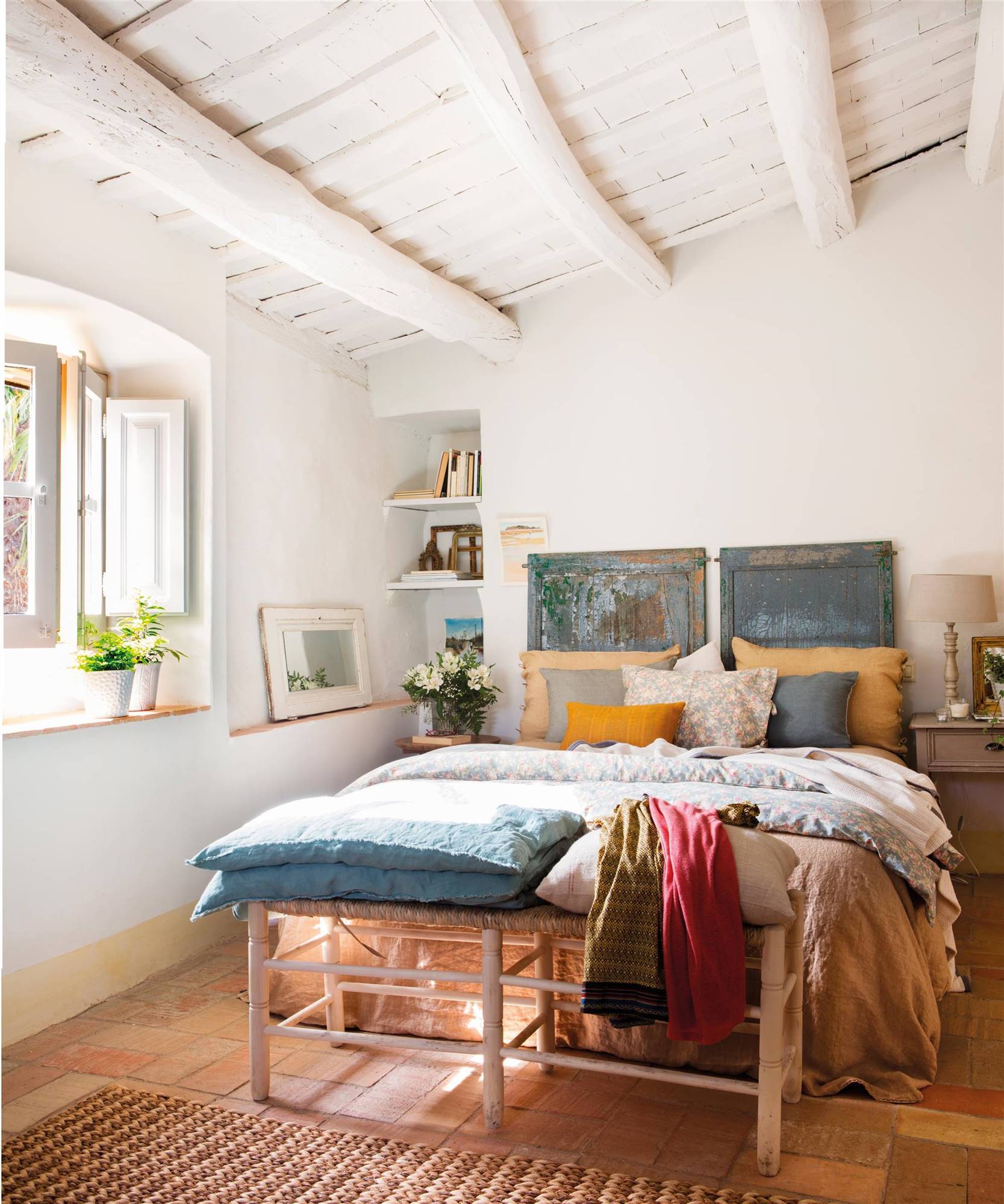 Dormitorio con banqueta, vigas en el techo y cabecero original recuperado con pintura a al tiza.