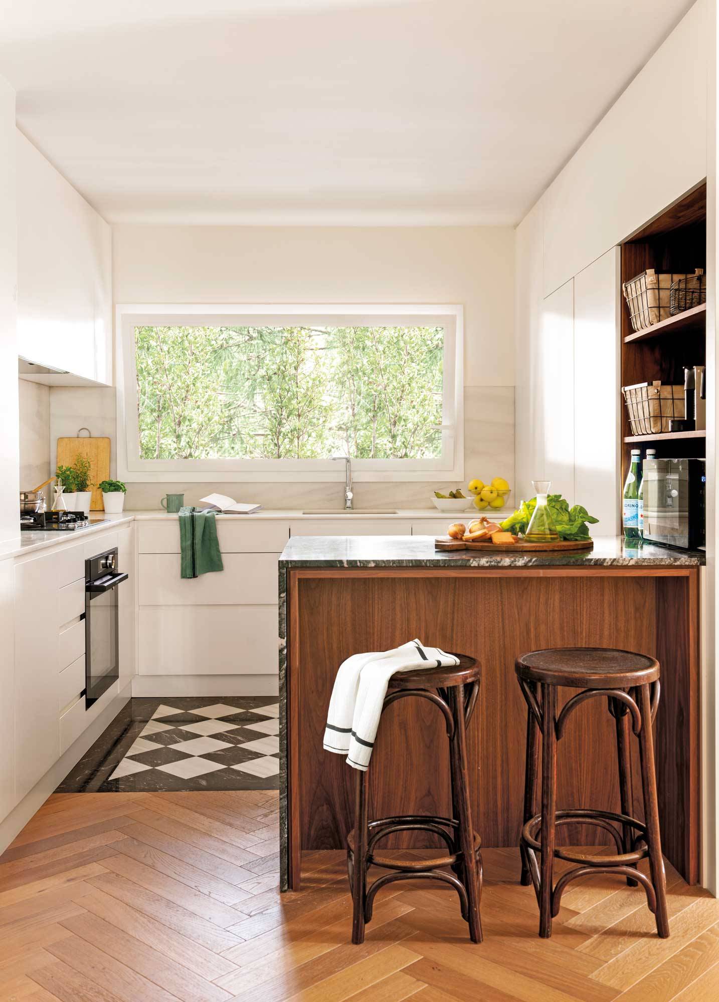 Cocina blanca pequeña con suelo de azulejos y madera, y pequeña barra con taburetes de madera.