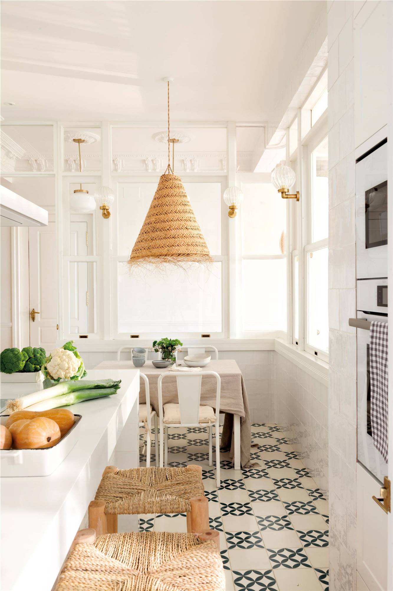 Cocina blanca con lámpara de fibra y suelo con baldosas hidráulicas geométricas. 