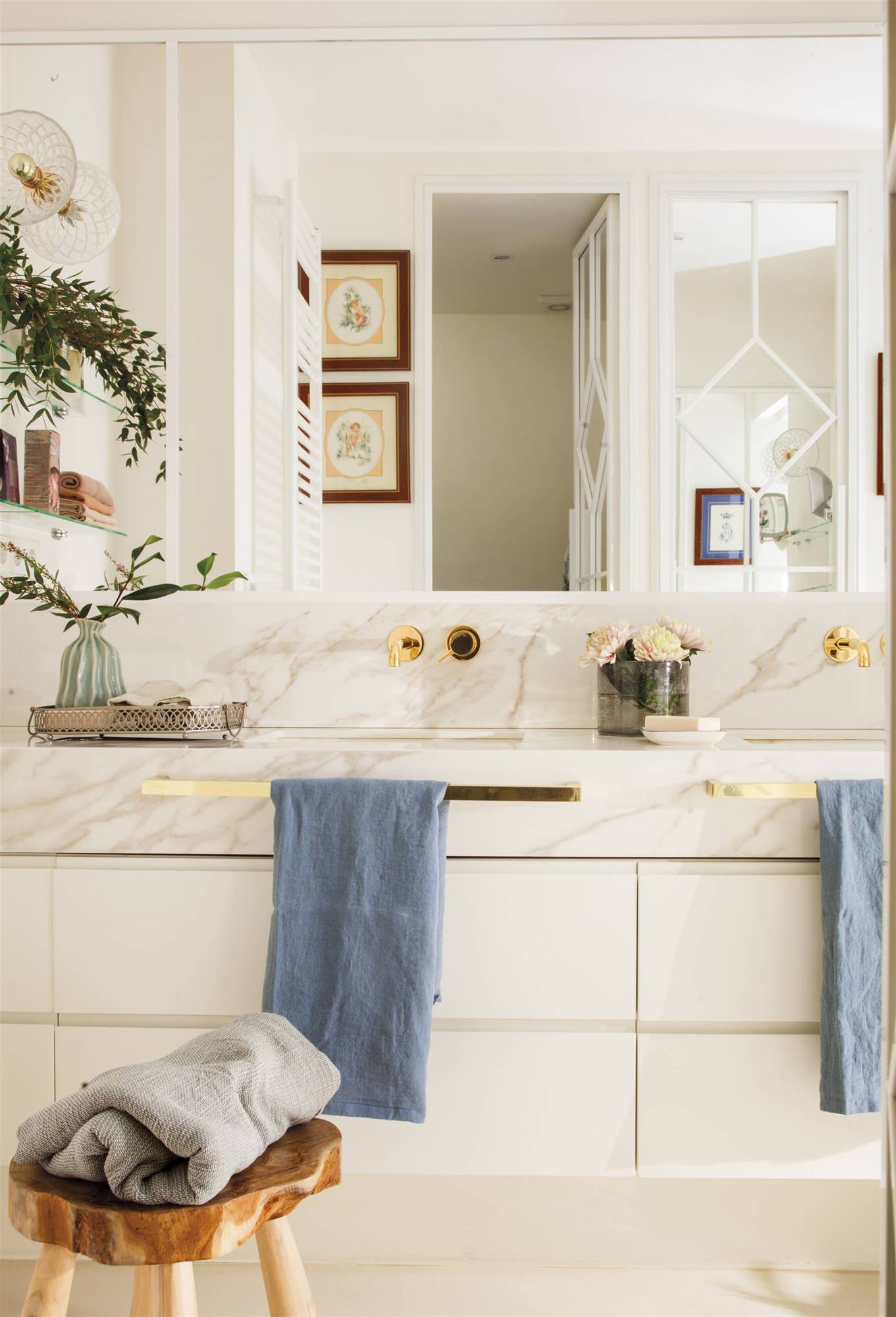 Baño blanco con revestimiento en mármol y detalles dorados.