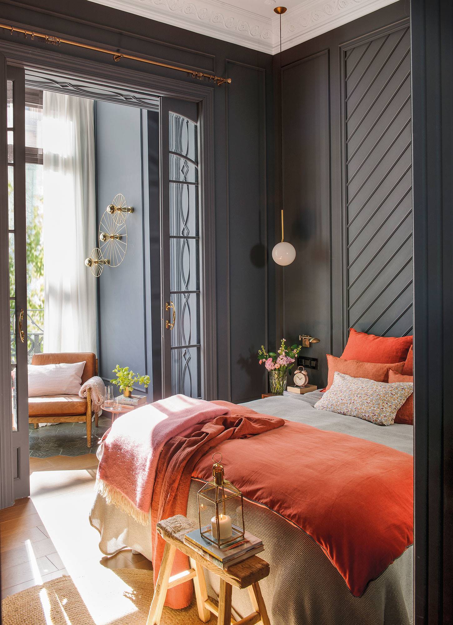 Dormitorio con paredes negras y ropa de cama naranja.