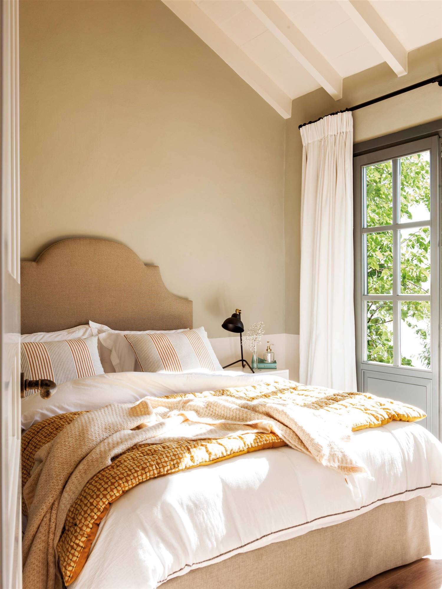 Dormitorio beige con cabecero tapizado.