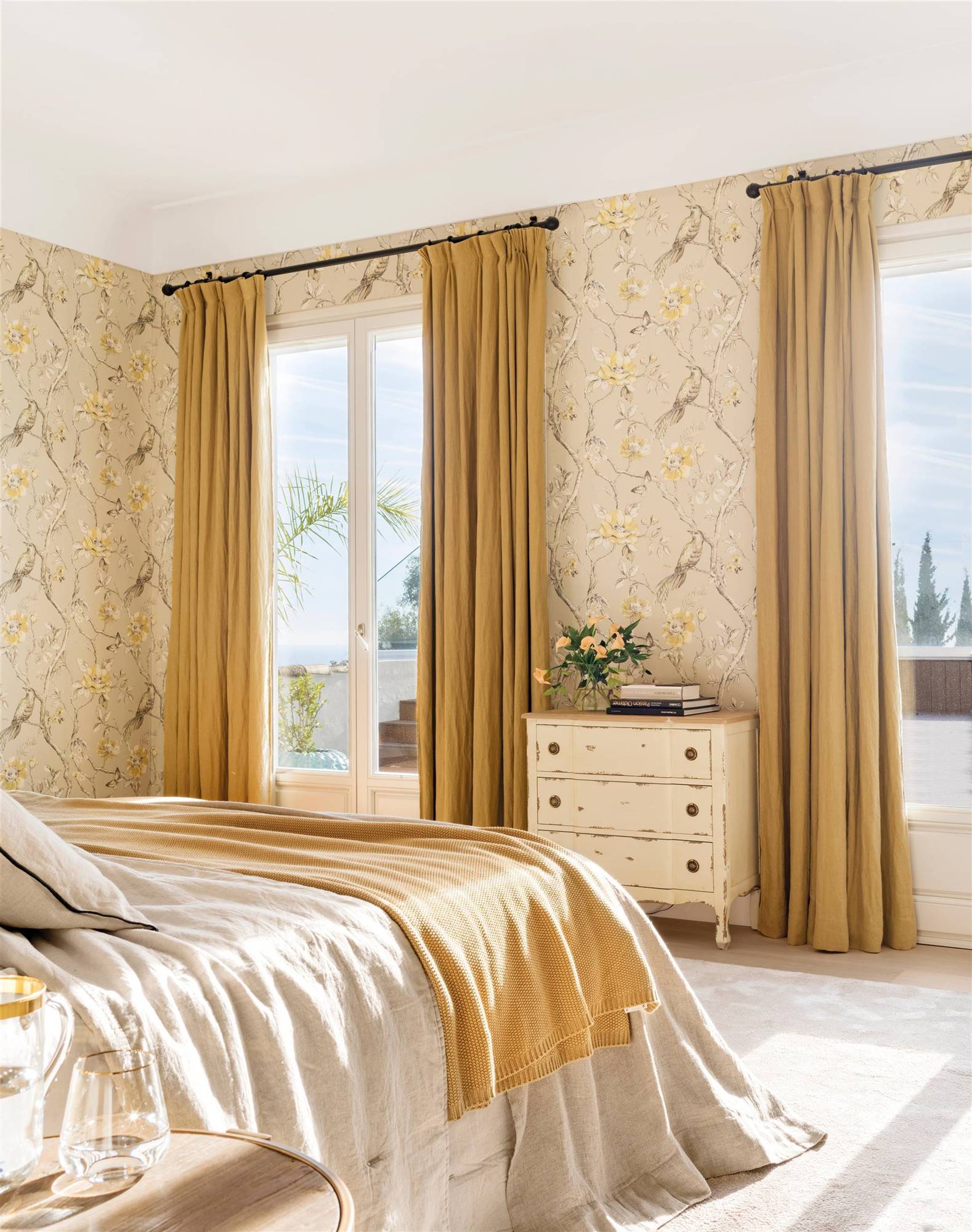 Dormitorio con cortinas con caída en amarillo y con papel pintado. 
