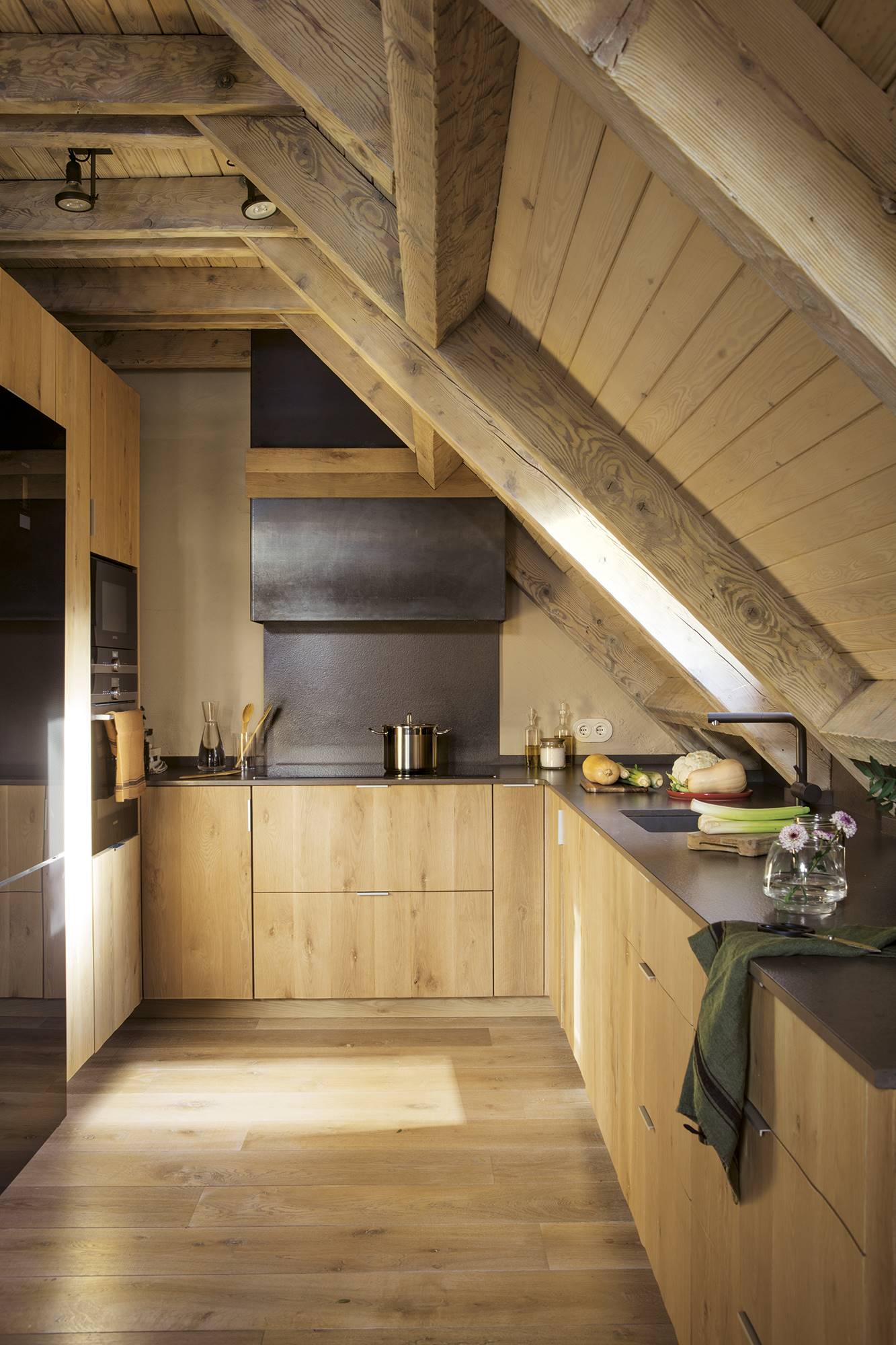 Cocina de madera con techos abuhardillado de madera. 